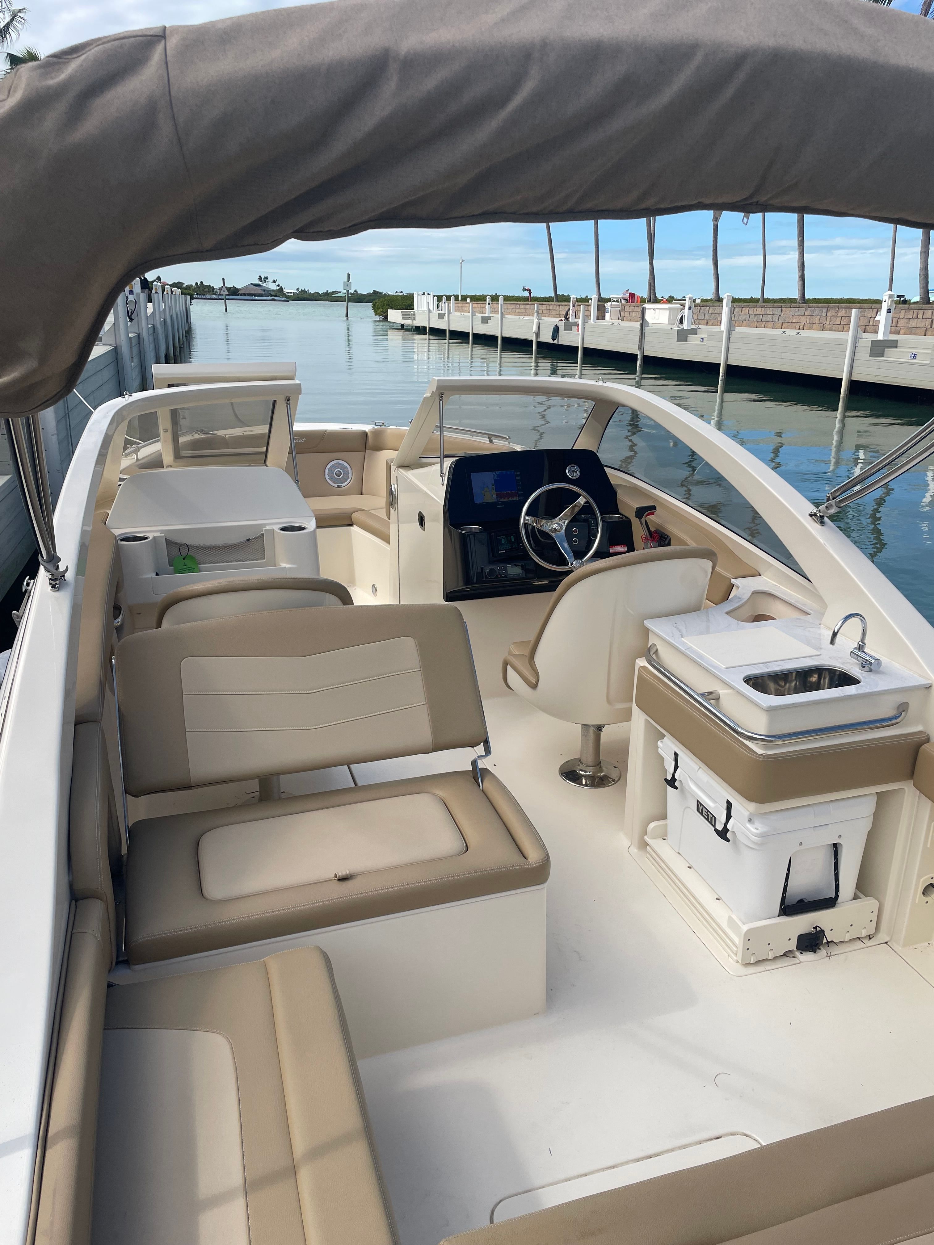 A 2020 Scout 235 Dorado boat with beige seating and a helm station, docked by the water.