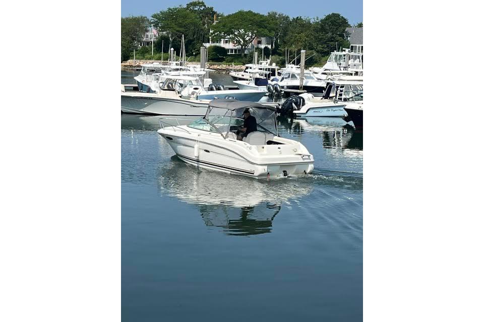 2004 Sea Ray 215 Weekender boat cruising in a marina with other vessels.
