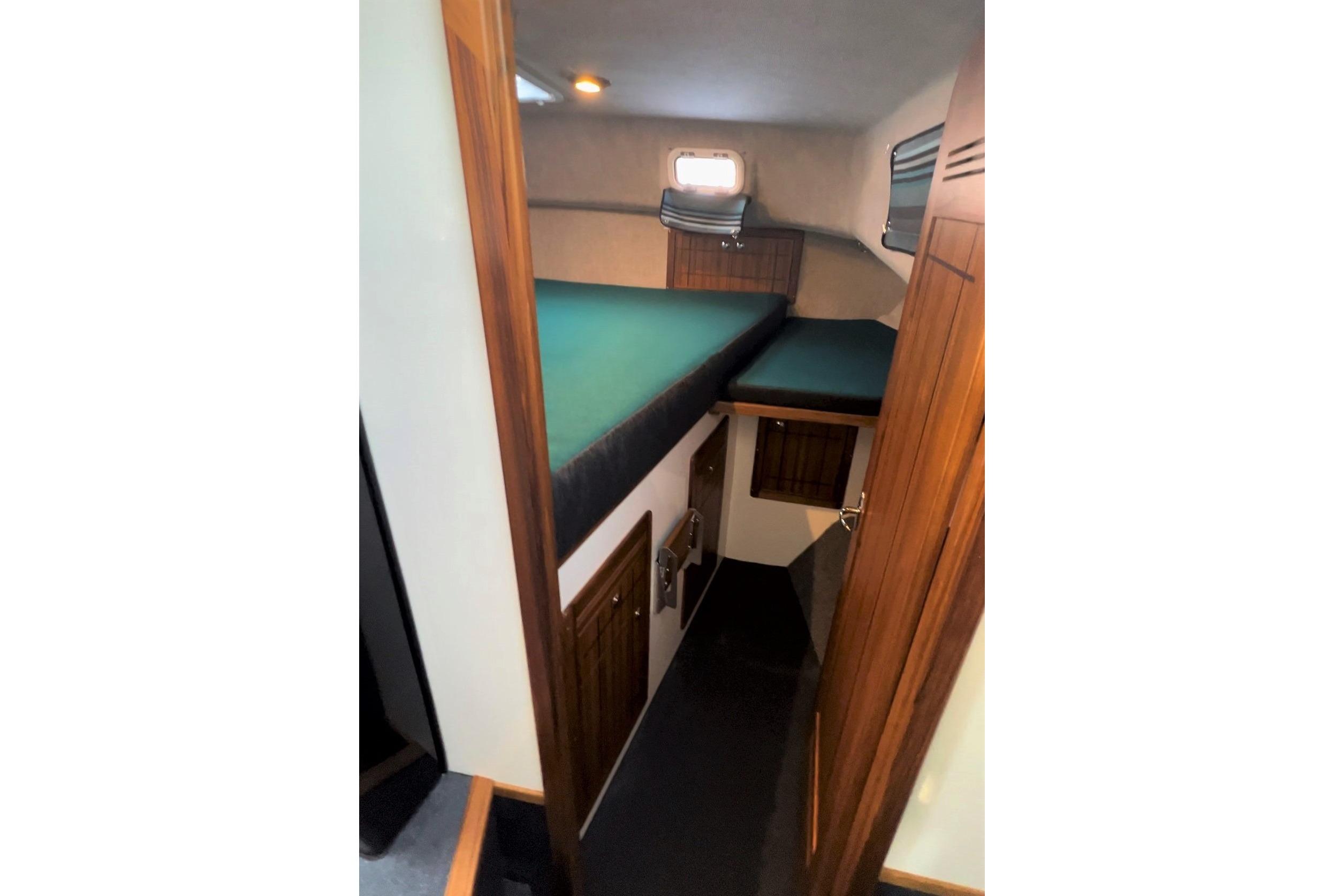 Interior cabin of 2026 Sea Sport Pacific 3200 boat with wooden accents and green bedding.