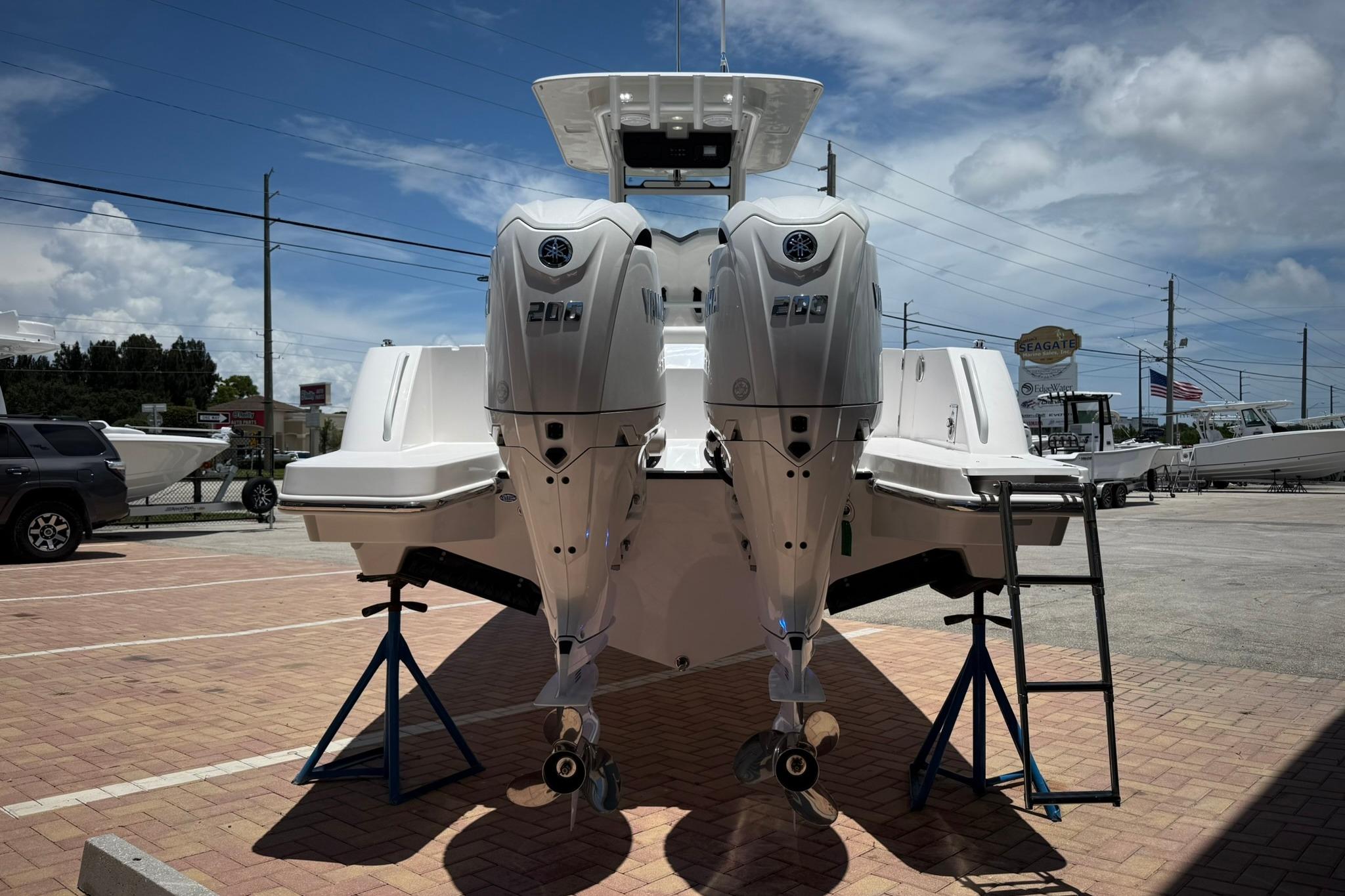 2026 Edgewater 250CC boat with dual outboard engines on display in a sunny marina.
