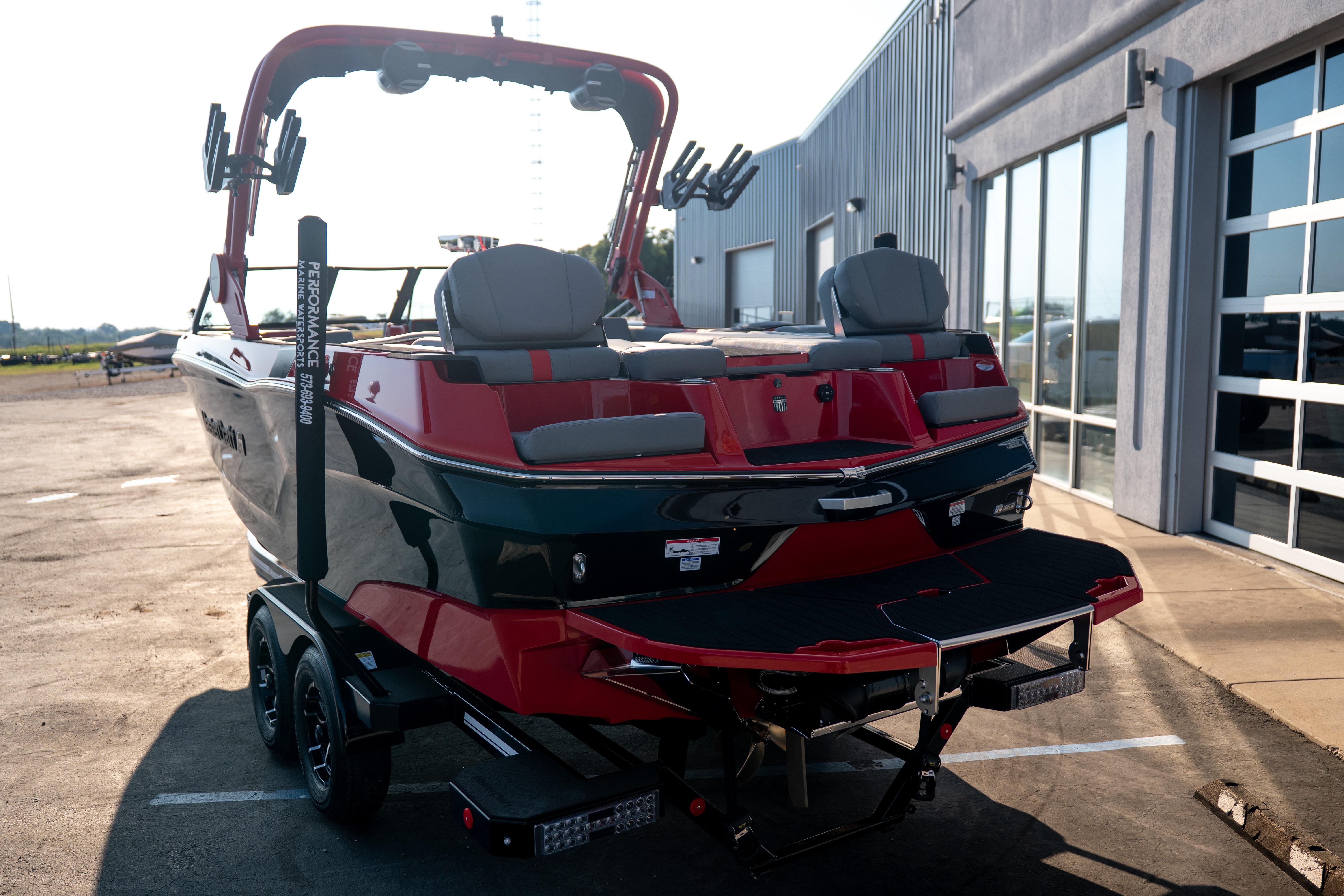 2027 MasterCraft XT24 boat on trailer, parked outside a modern building.