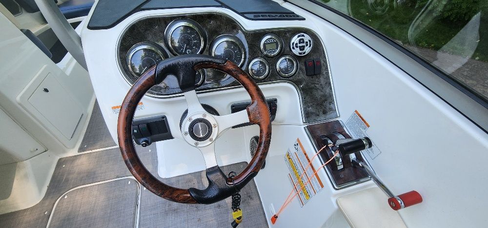 The image shows a Sea-Doo sport boat cockpit with a sleek wood steering wheel and instruments.