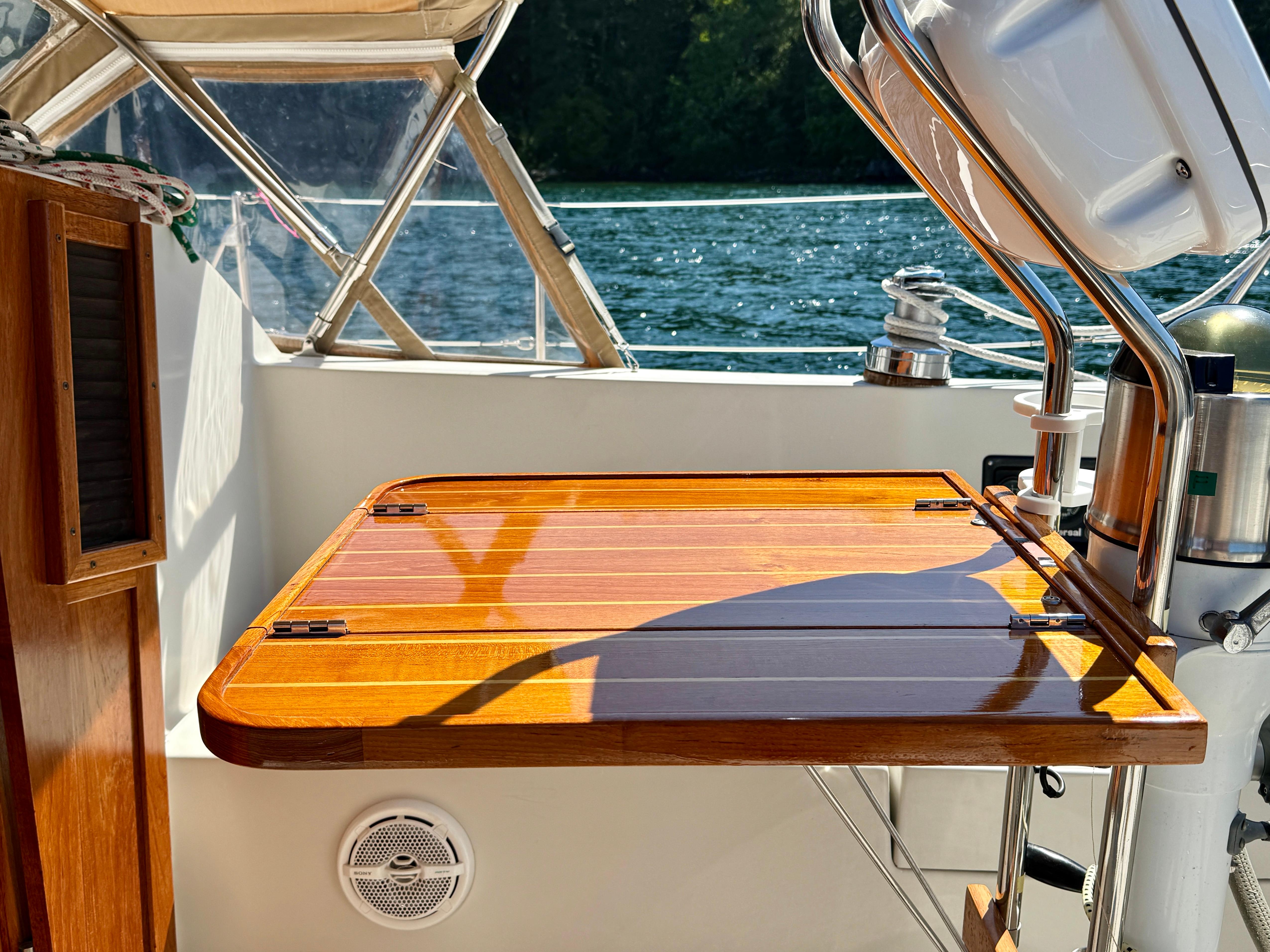 Polished wooden table on 1989 Nonsuch 30 Ultra sailboat, with scenic water view.