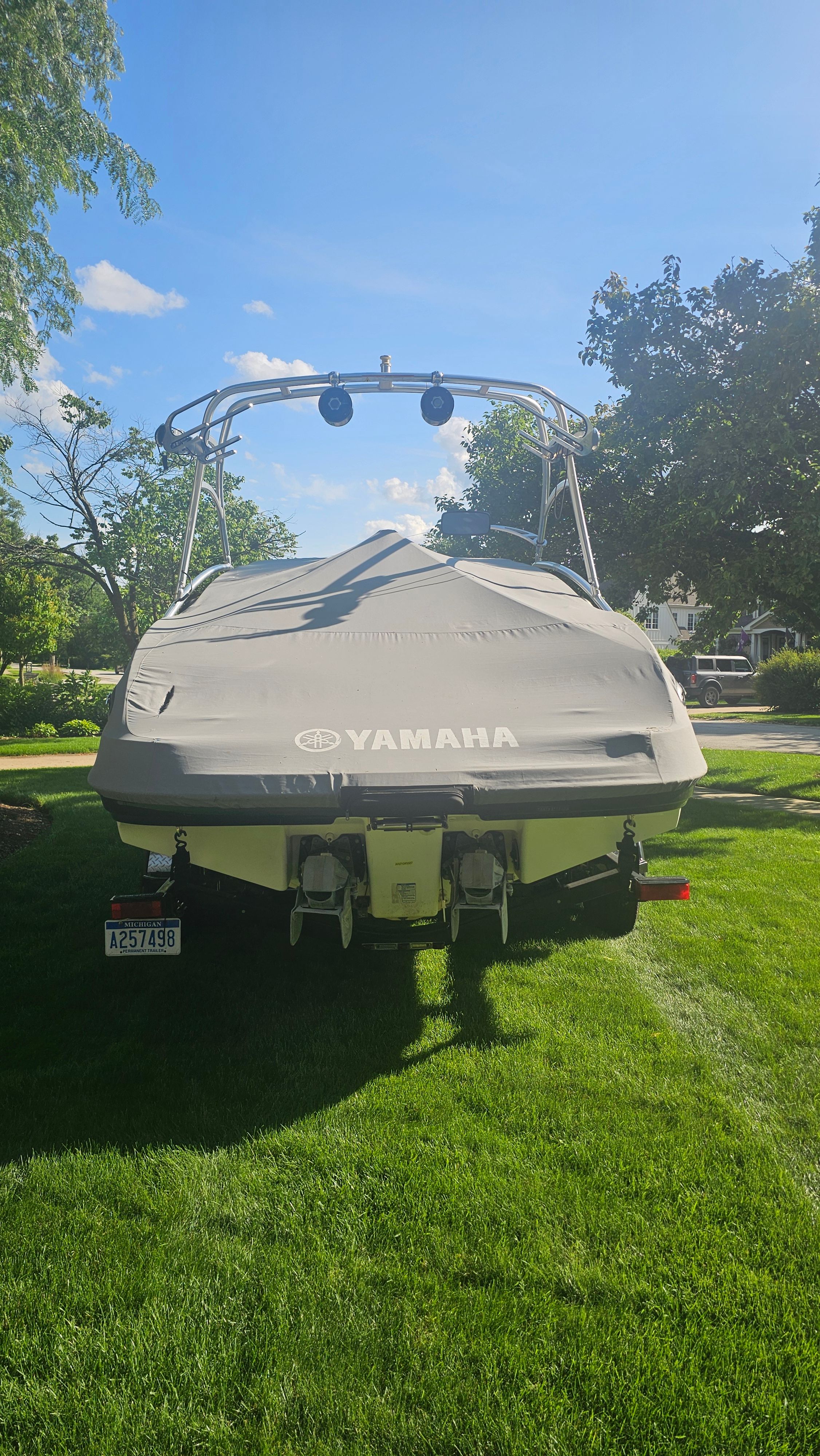 A 2010 Yamaha AR210 boat is on a green lawn, covered with a protective cover.