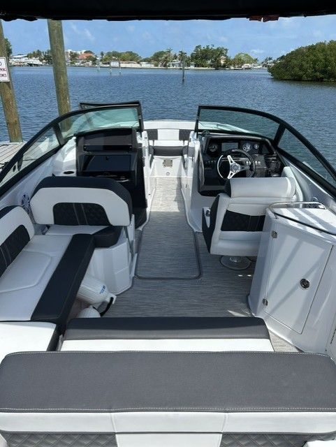 Interior view of a modern boat with white and black seating, docked on calm water.