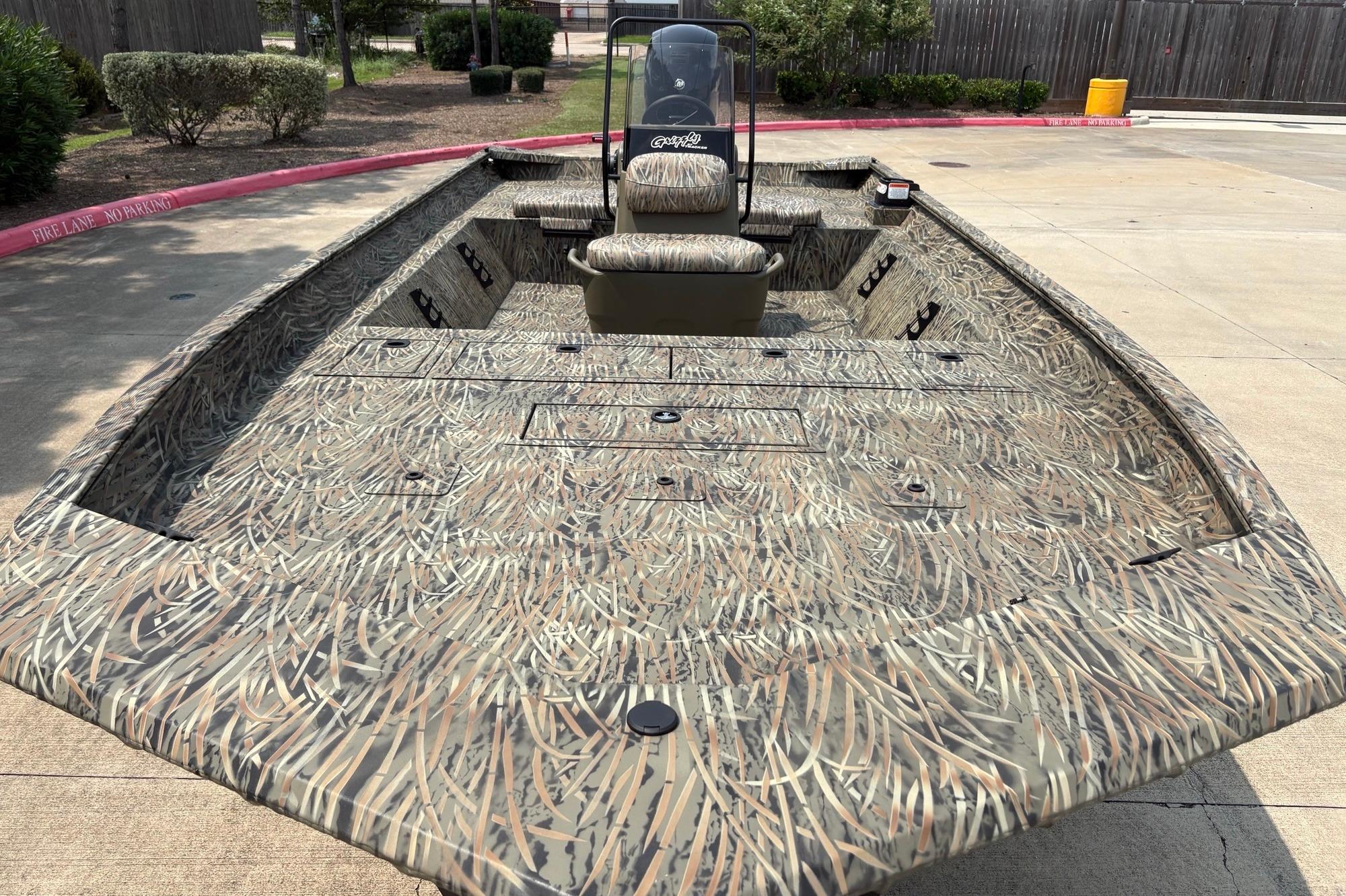 2026 Tracker Grizzly 2072 CC boat with camouflage design in a parking area.