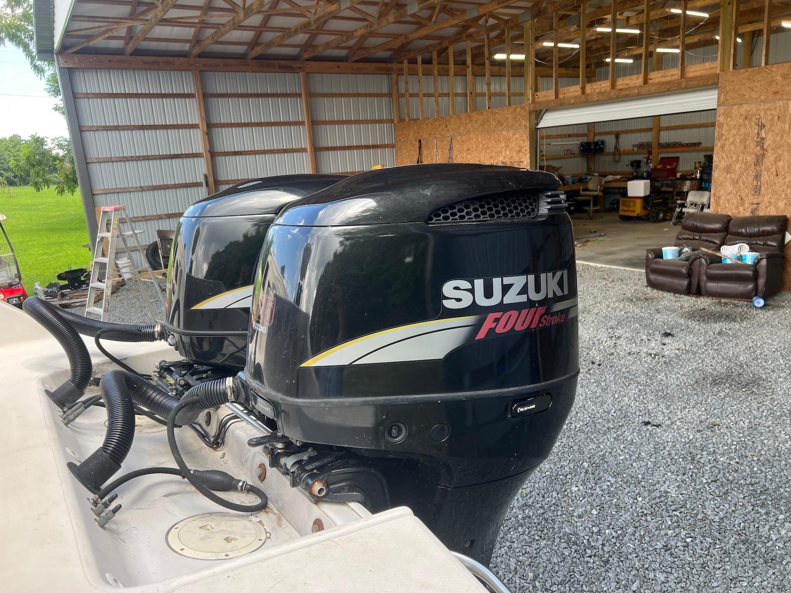 Twin Suzuki Four Stroke engines on a 1997 Pro-Line 2810 Walkaround boat in a garage.