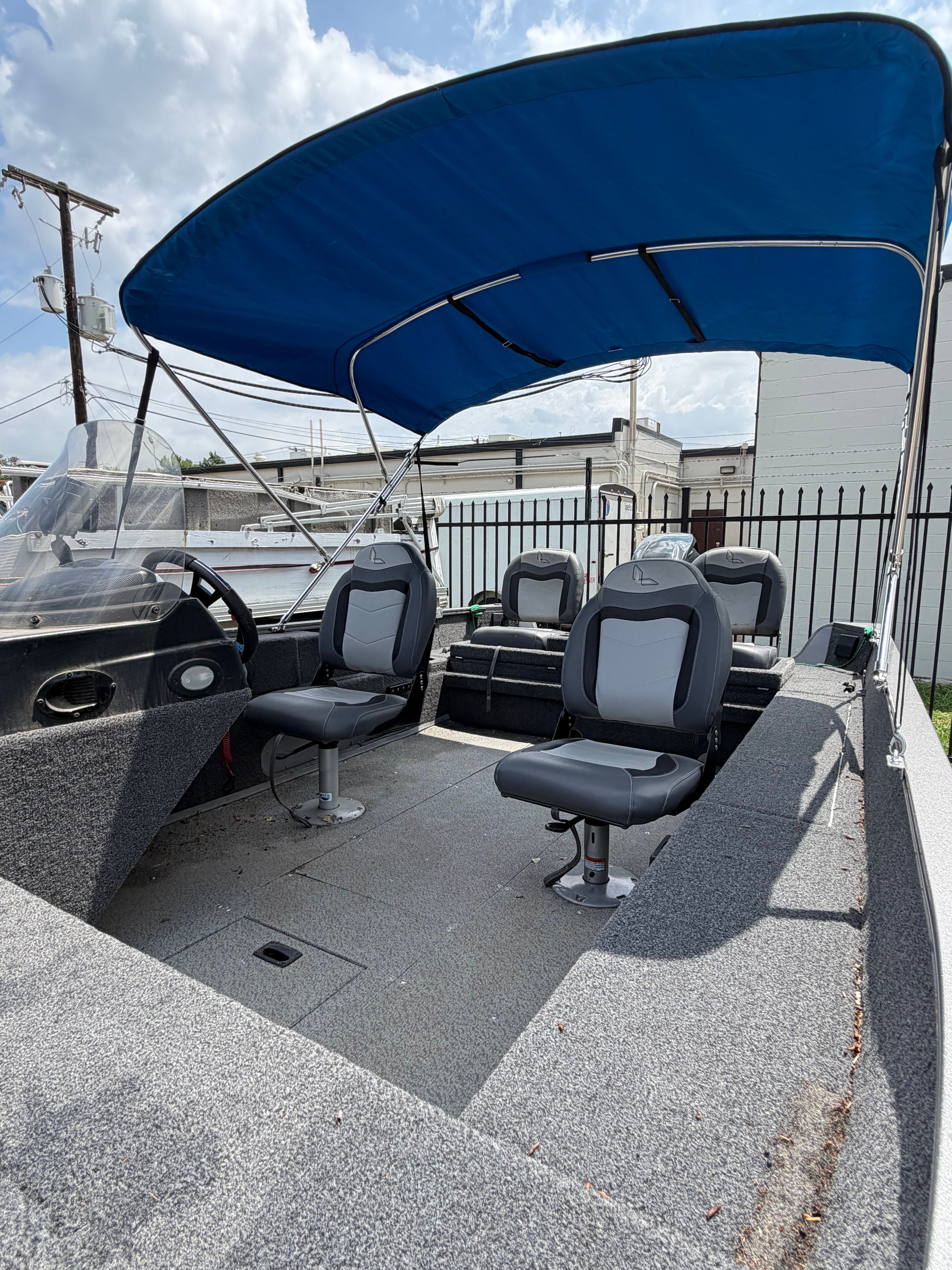 The image shows a Lowe Fishing Machine 1675SC boat with blue sunshade and gray seats.