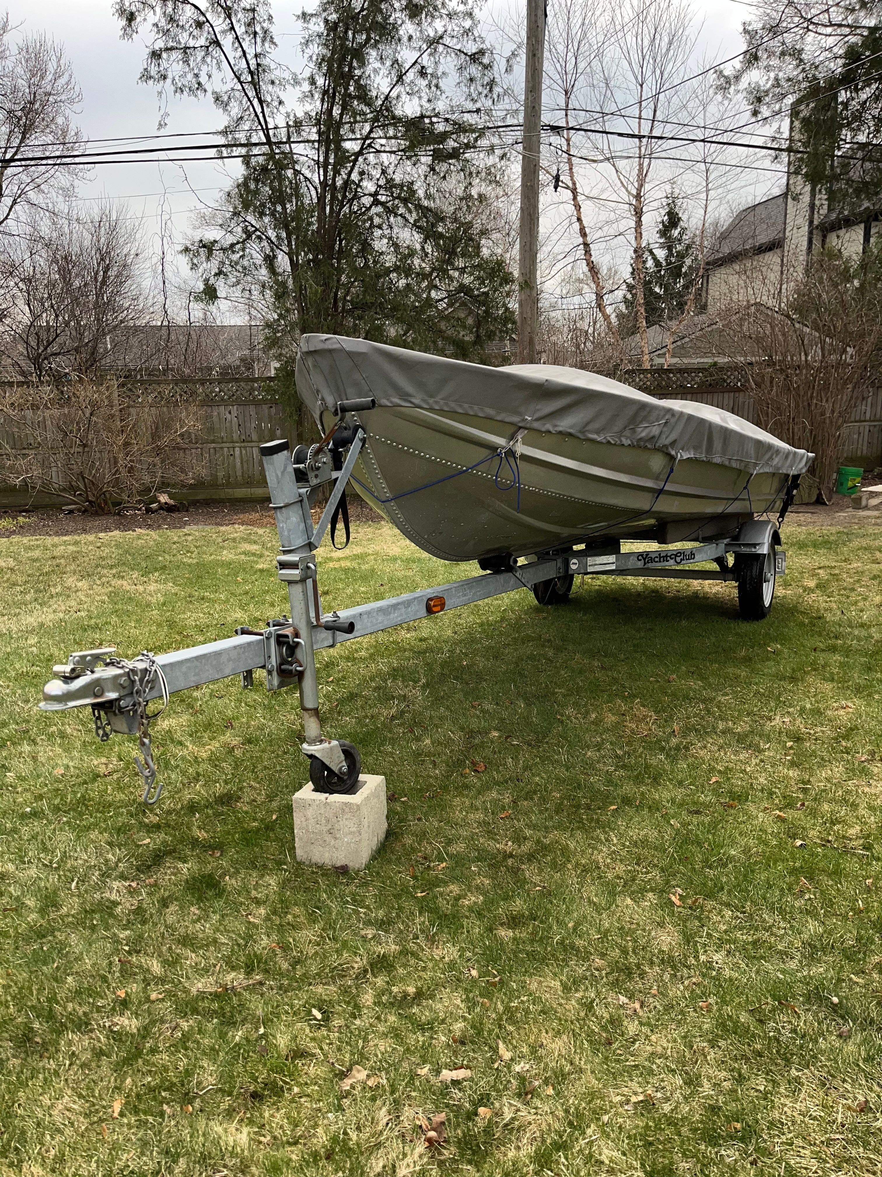 A 2005 Polar Kraft V1460 boat on a trailer in a yard.