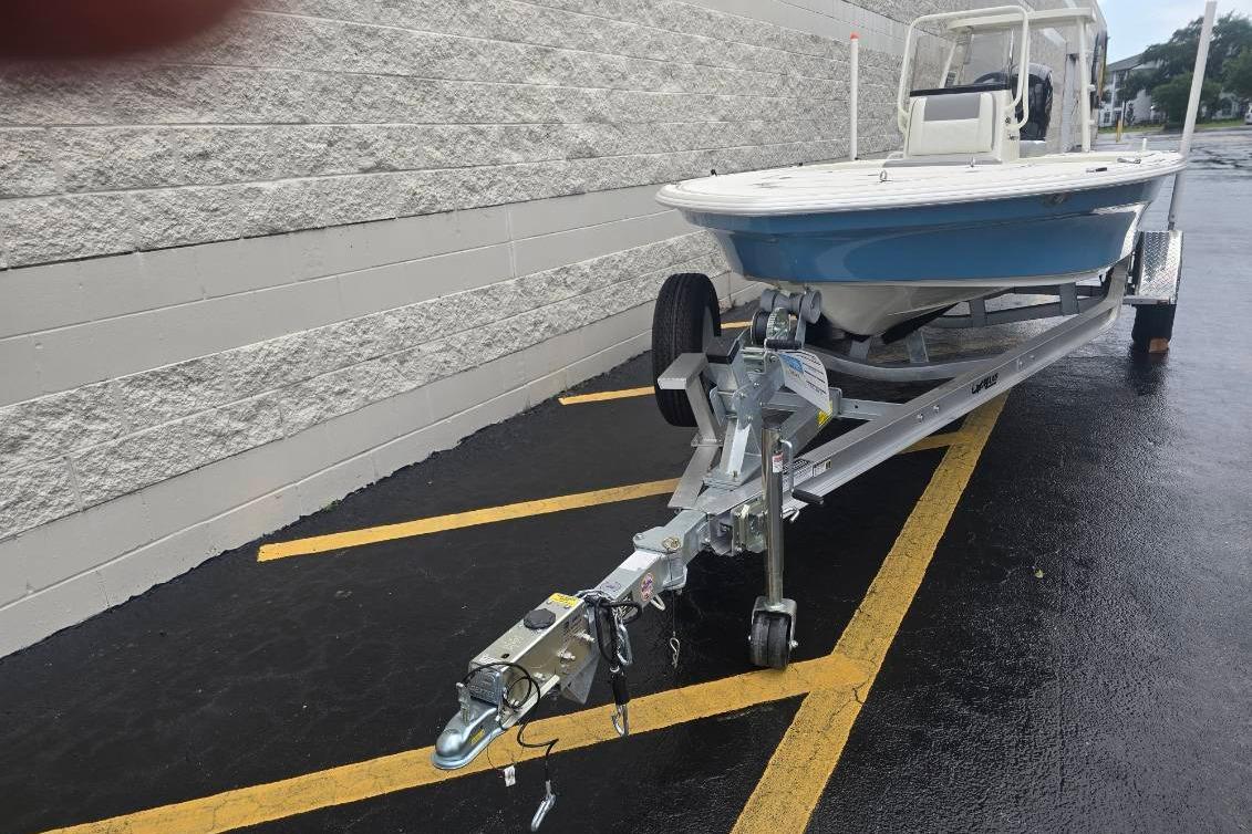 2026 Mako 18 Pro Skiff on trailer, parked on wet pavement near a brick wall.