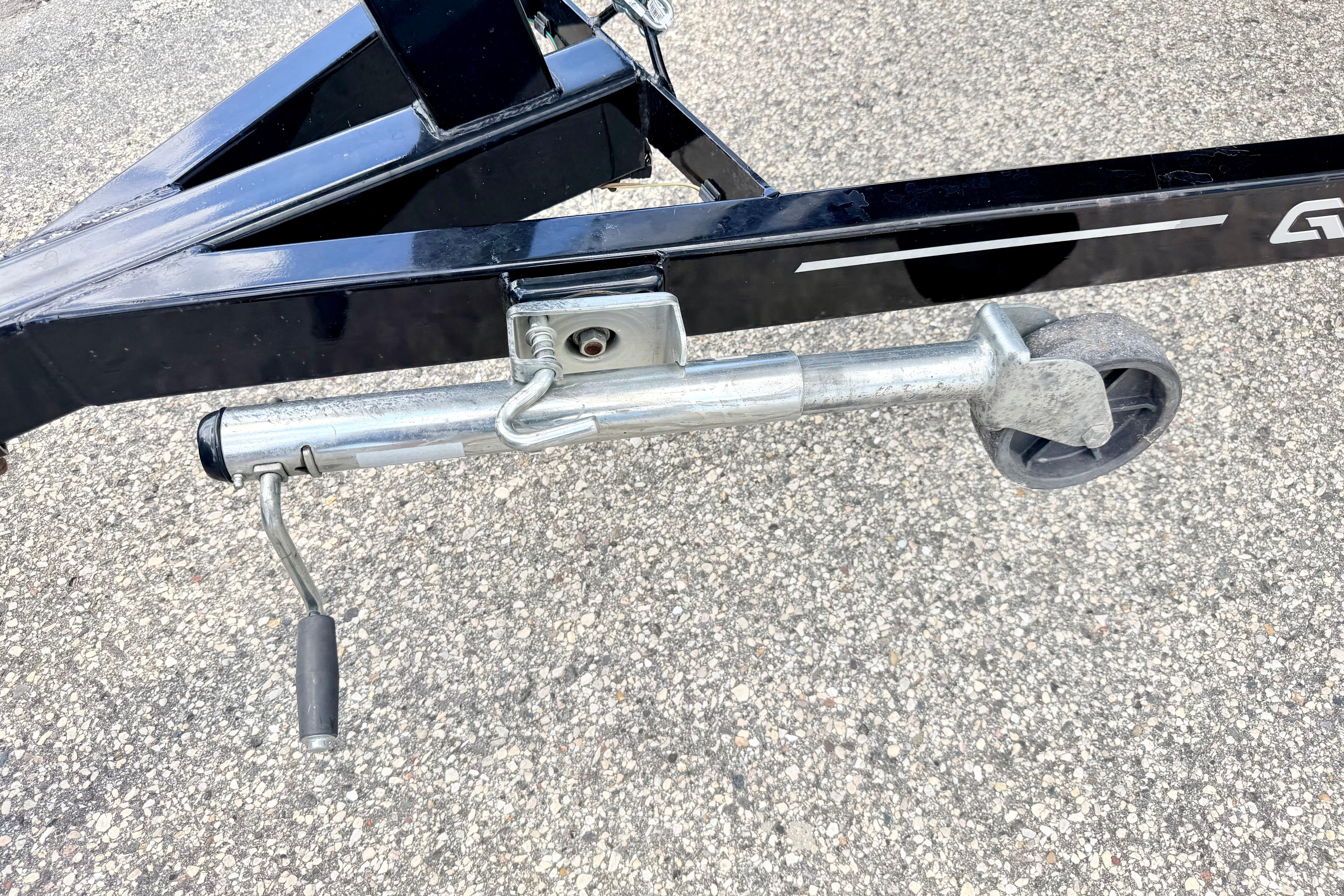Trailer jack on a 2018 Glastron GT 185 boat trailer, parked on asphalt.