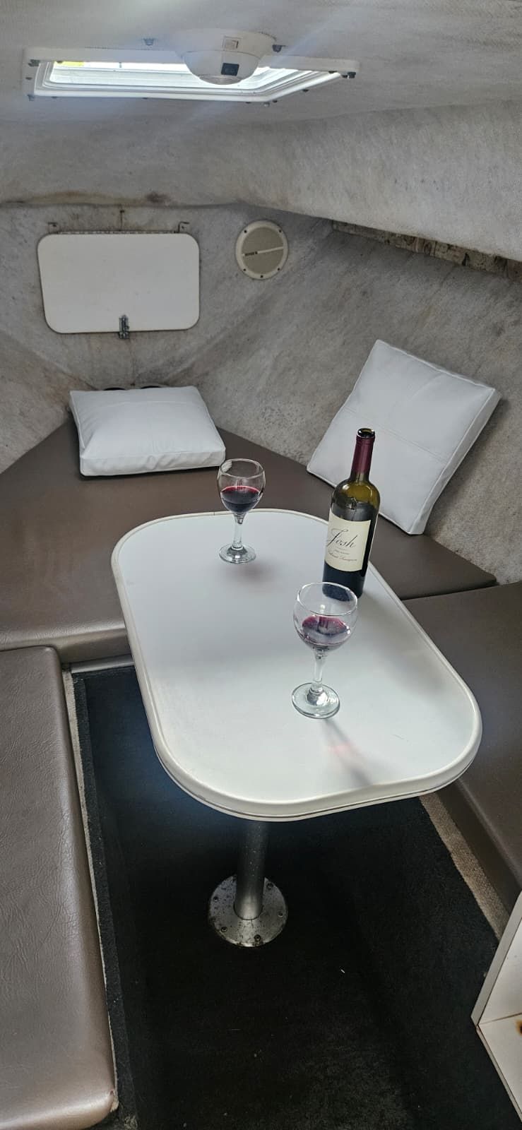 Interior of Wellcraft 24 Walkaround boat with table and wine glasses.