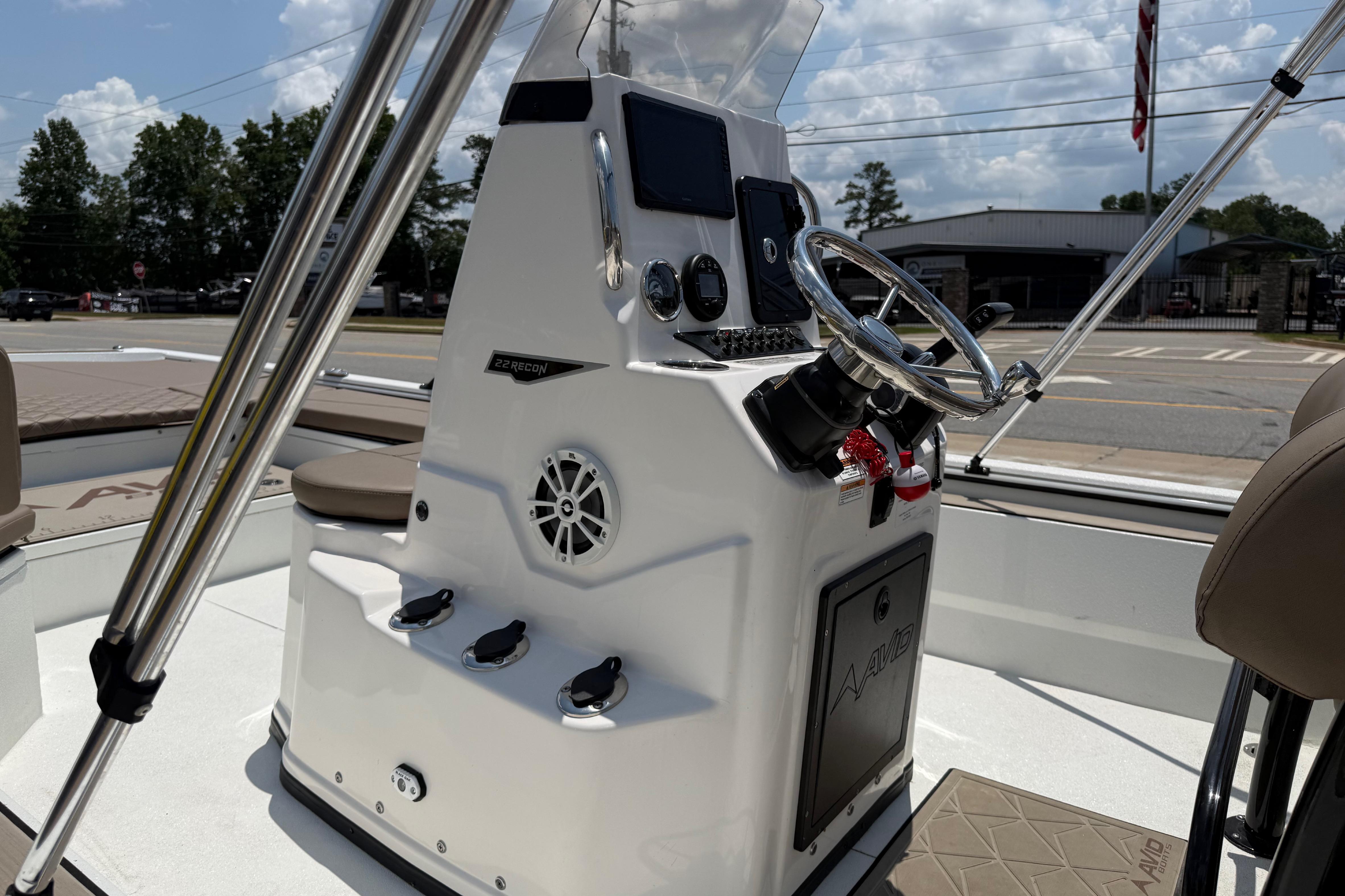 2025 Avid 22 Recon boat console with steering wheel and controls, docked outdoors.