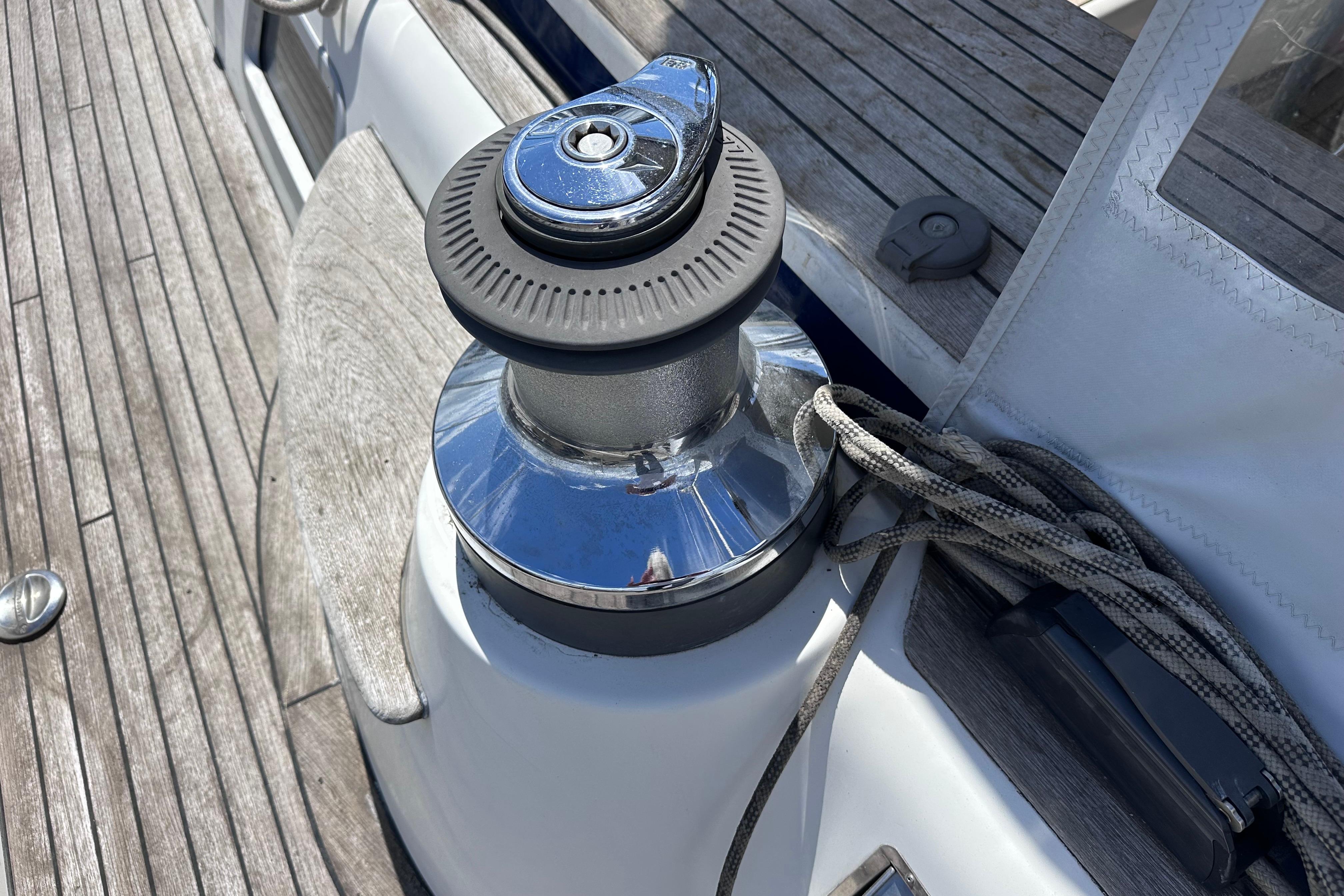 Winch on 2008 Hallberg-Rassy 54 yacht deck with wooden finish and ropes.