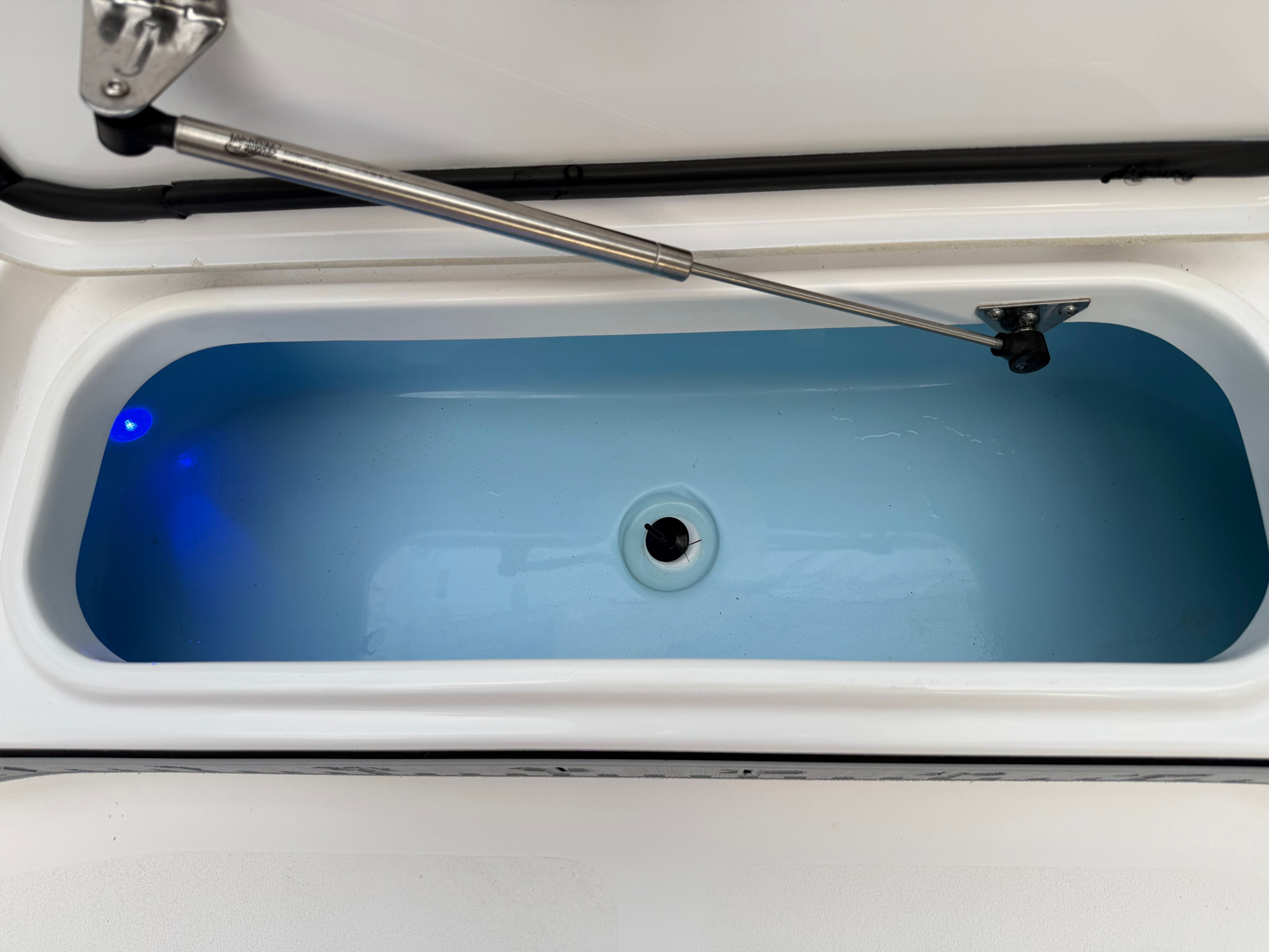 An open storage compartment with blue interior lining and hydraulic arm.
