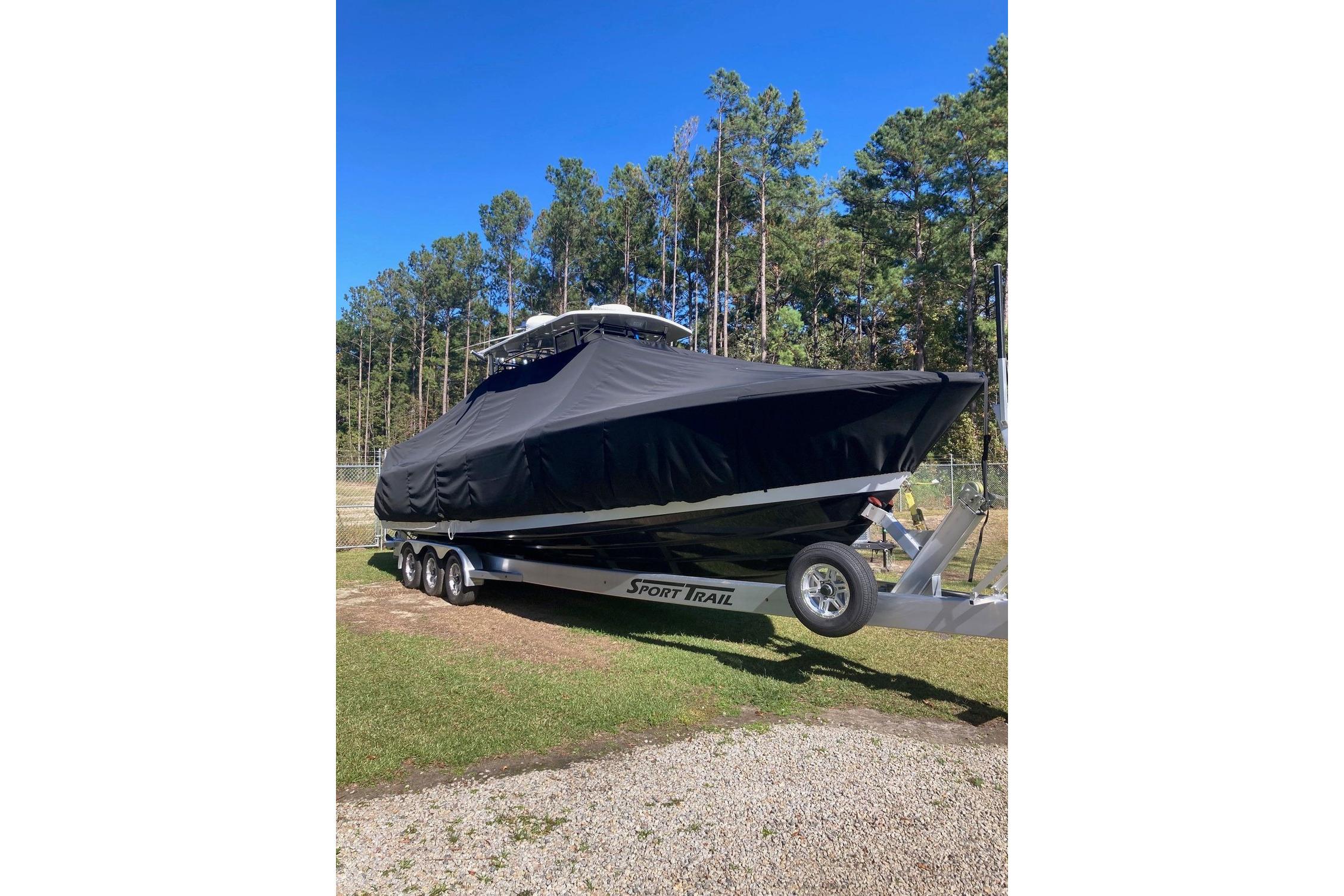 Covered 2022 Sea-Lion 34 TE boat on trailer, surrounded by trees.