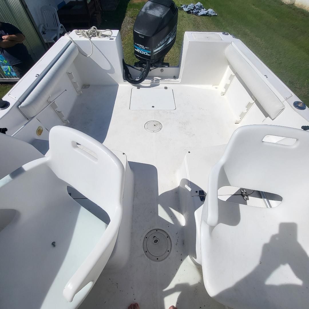The image shows the cockpit of a 1998 Sport-Craft 211WAC boat with white seats and an outboard motor.