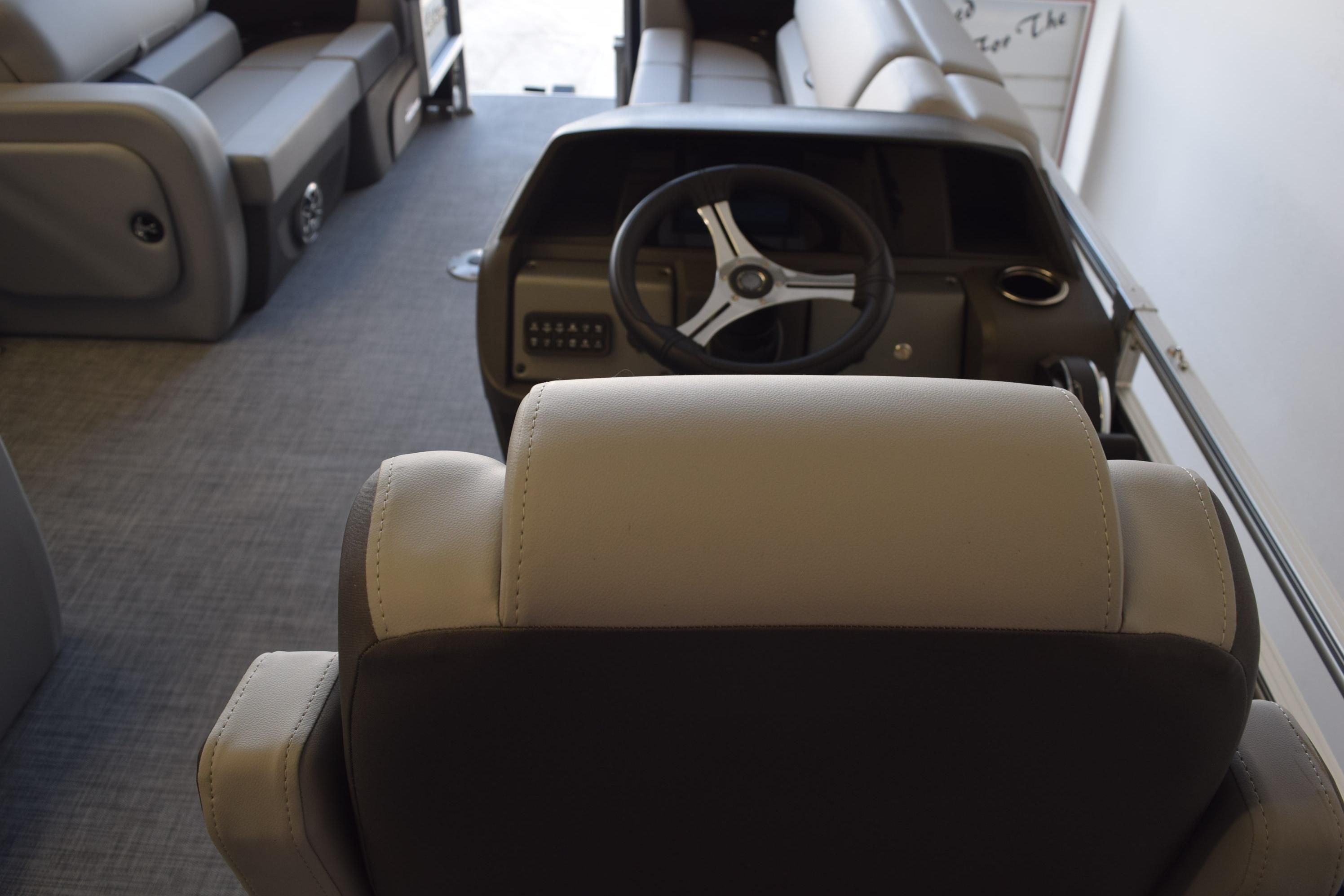Interior view of 2026 Sun Tracker SportFish 22 DLX boat, featuring steering wheel and seating.
