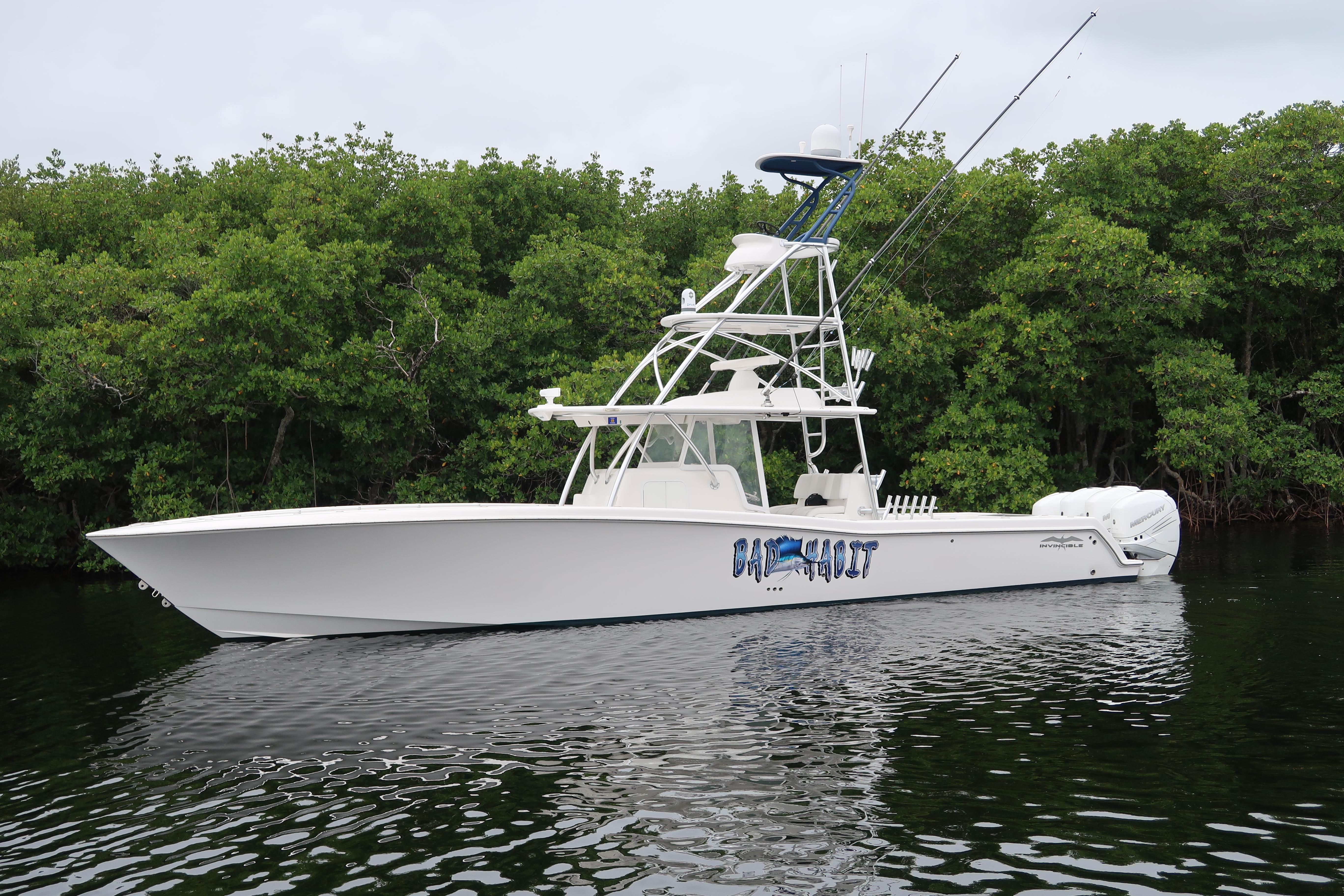 2016 Invincible 42 Open Fisherman boat on calm water near lush greenery.