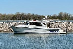 2017 Cutwater C-30 Sedan boat on calm water near rocky shoreline.