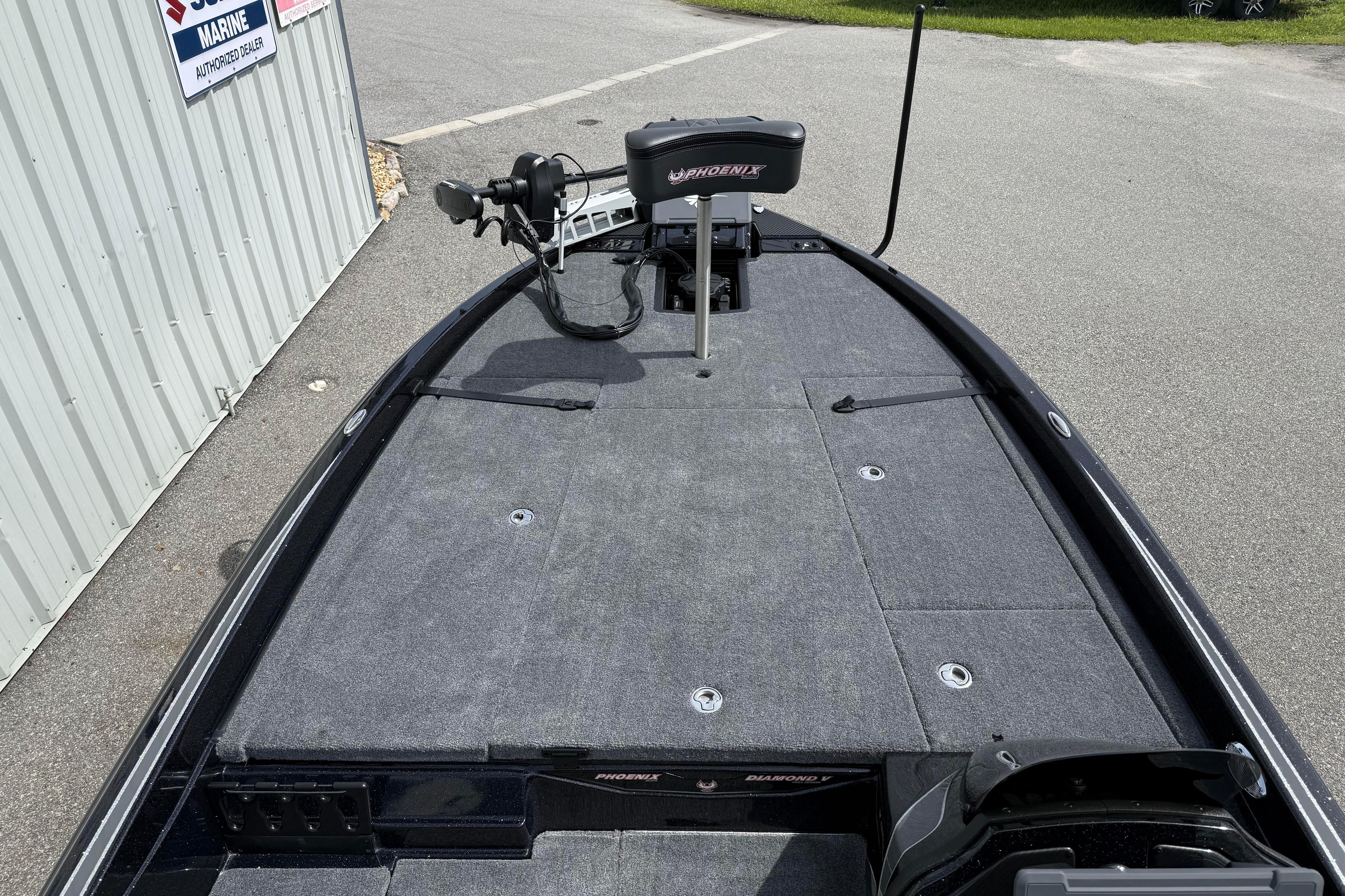 2027 Phoenix 921 Elite X boat deck with trolling motor, parked near a marine dealership.