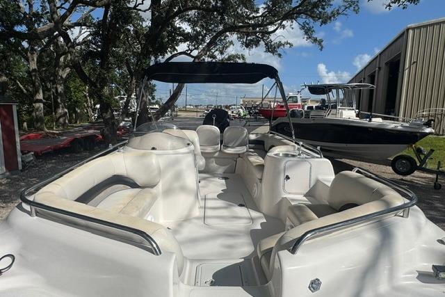 1999 Hurricane SunDeck Sport 201 OB boat with spacious seating, docked outdoors under a clear sky.