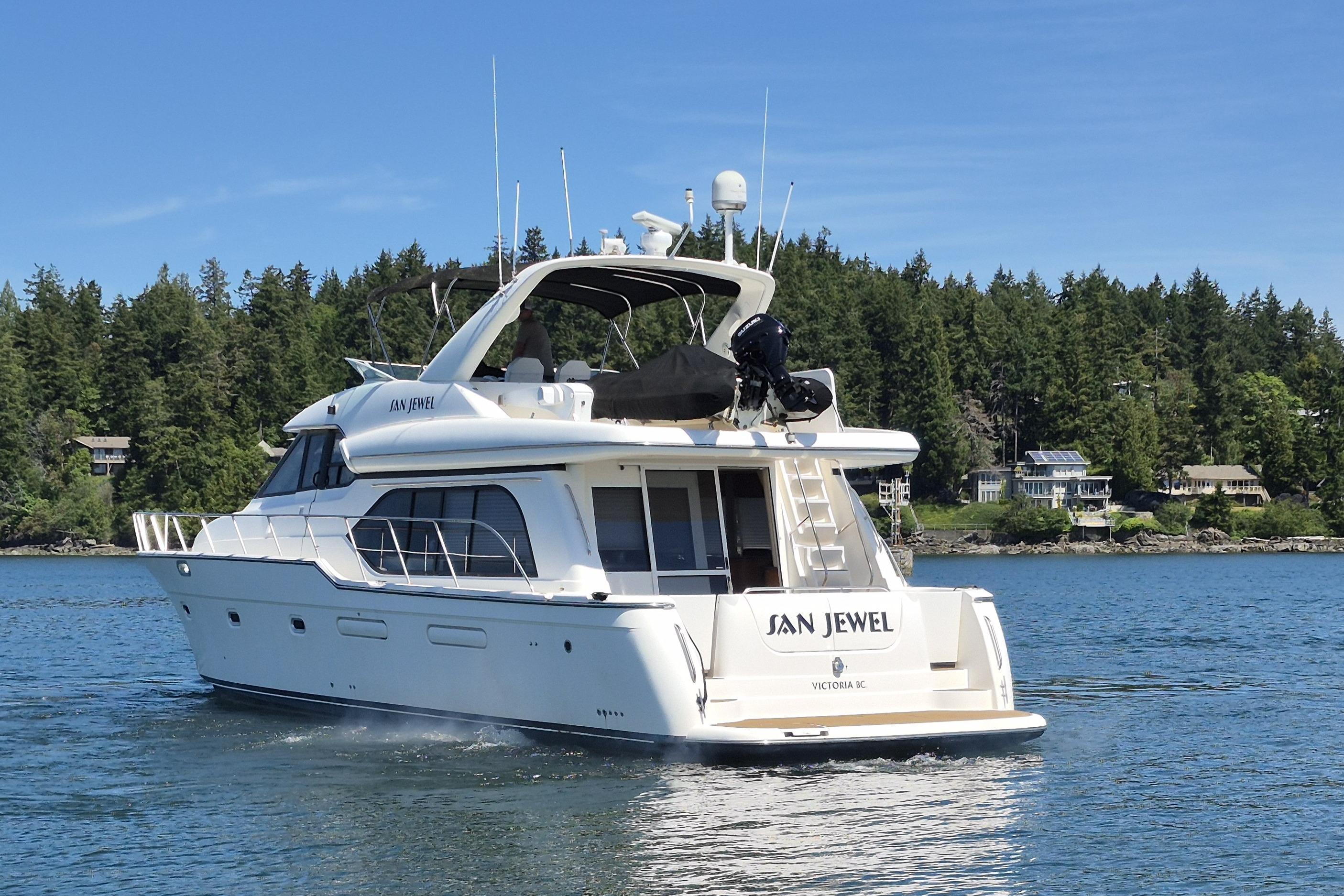 1998 Bayliner 5788 Pilot House Motoryacht cruising on a serene lake with forested shoreline.