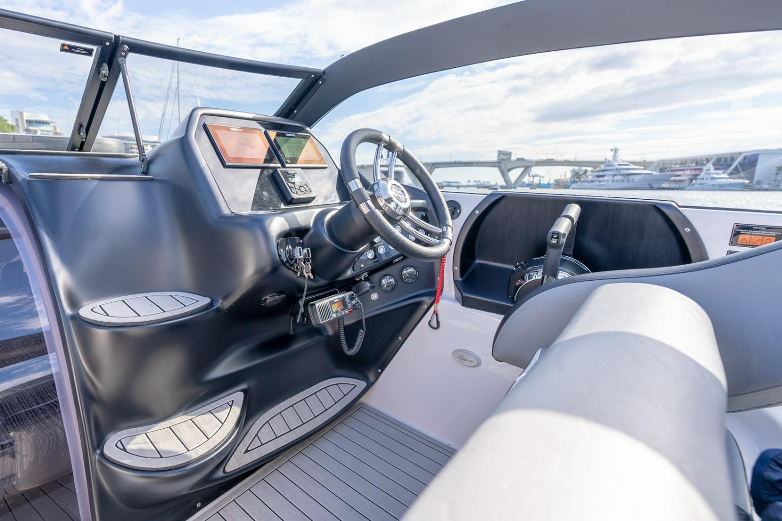 Interior view of a 2027 Hanover 305 boat cockpit with modern controls and steering wheel.