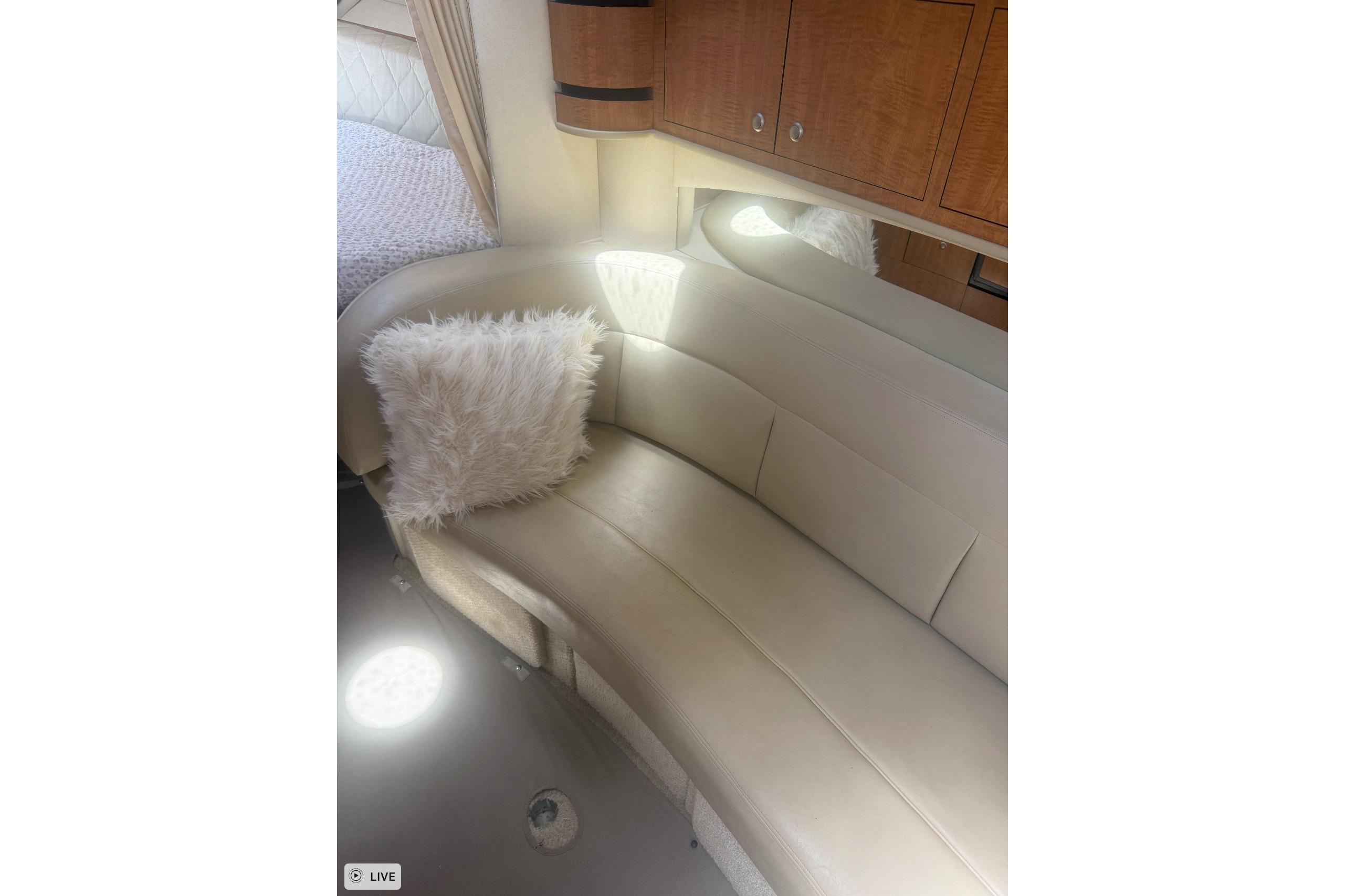 Interior of 2006 Sea Ray 300 Sundancer with beige seating and fluffy pillow.