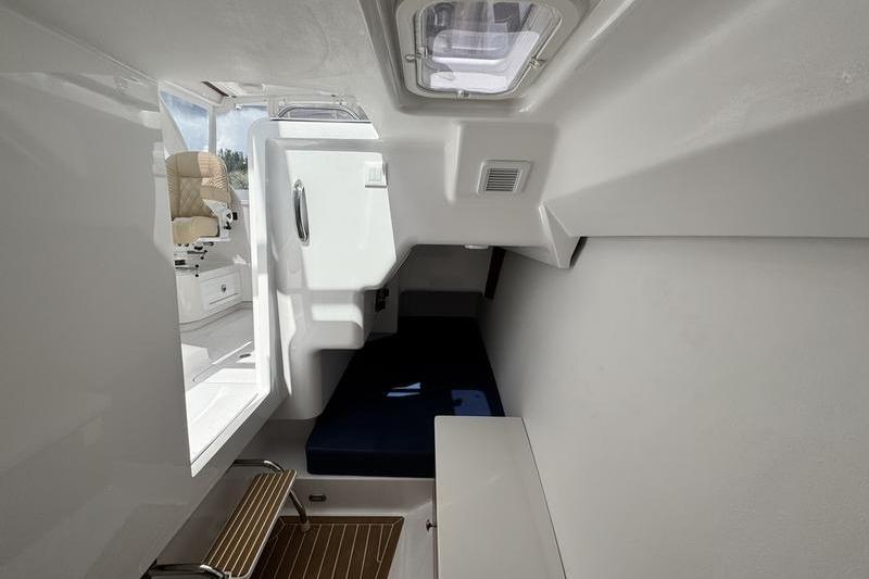 Interior cabin of 2026 Southport 33 DC boat, featuring seating and a window.