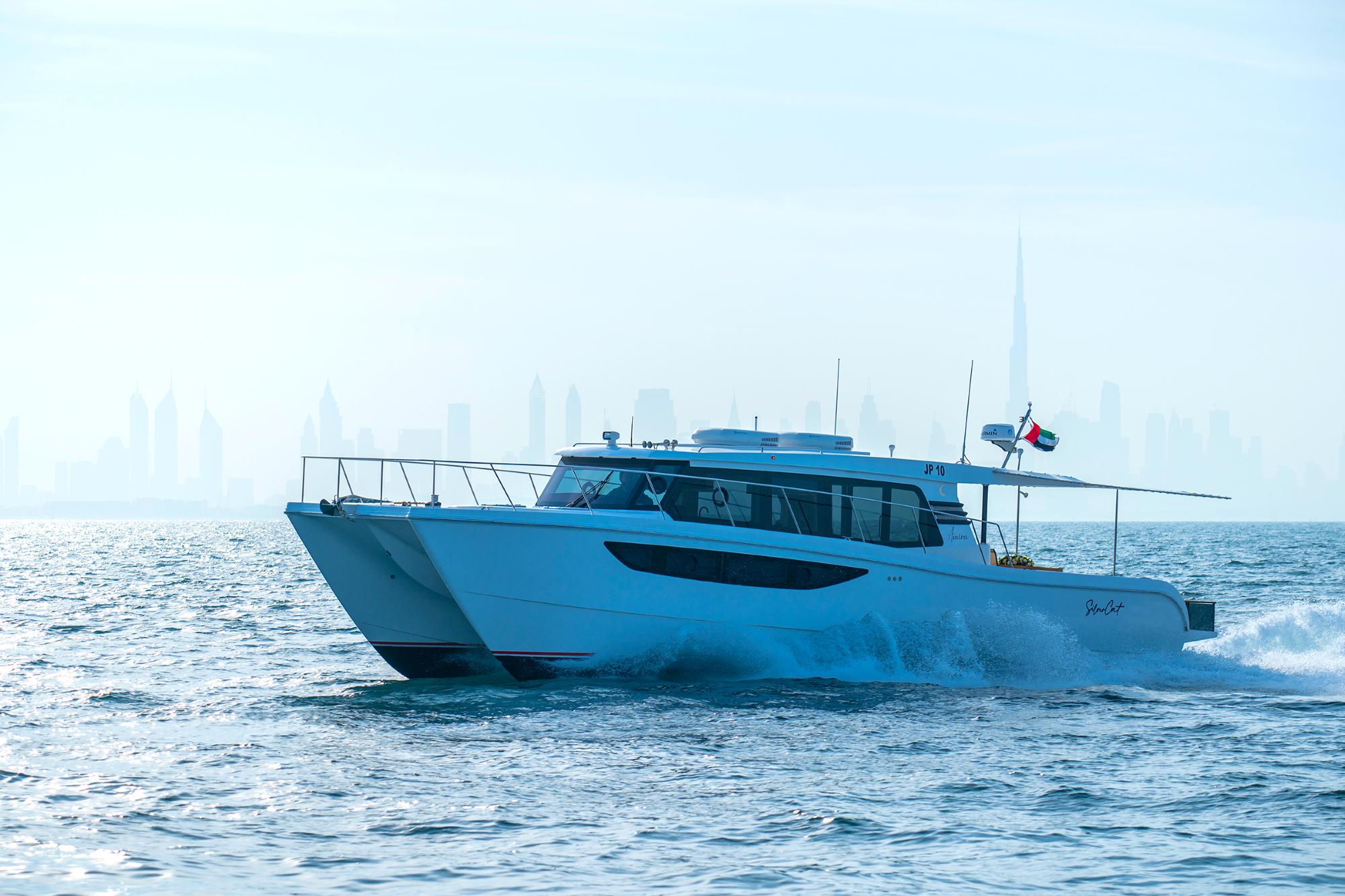 Custom SilverCAT 46LUX yacht cruising on open water, 2025 model, city skyline in background.