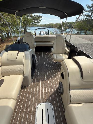2022 Premier 250 Solaris pontoon boat with beige seating and canopy, docked by a scenic lake.