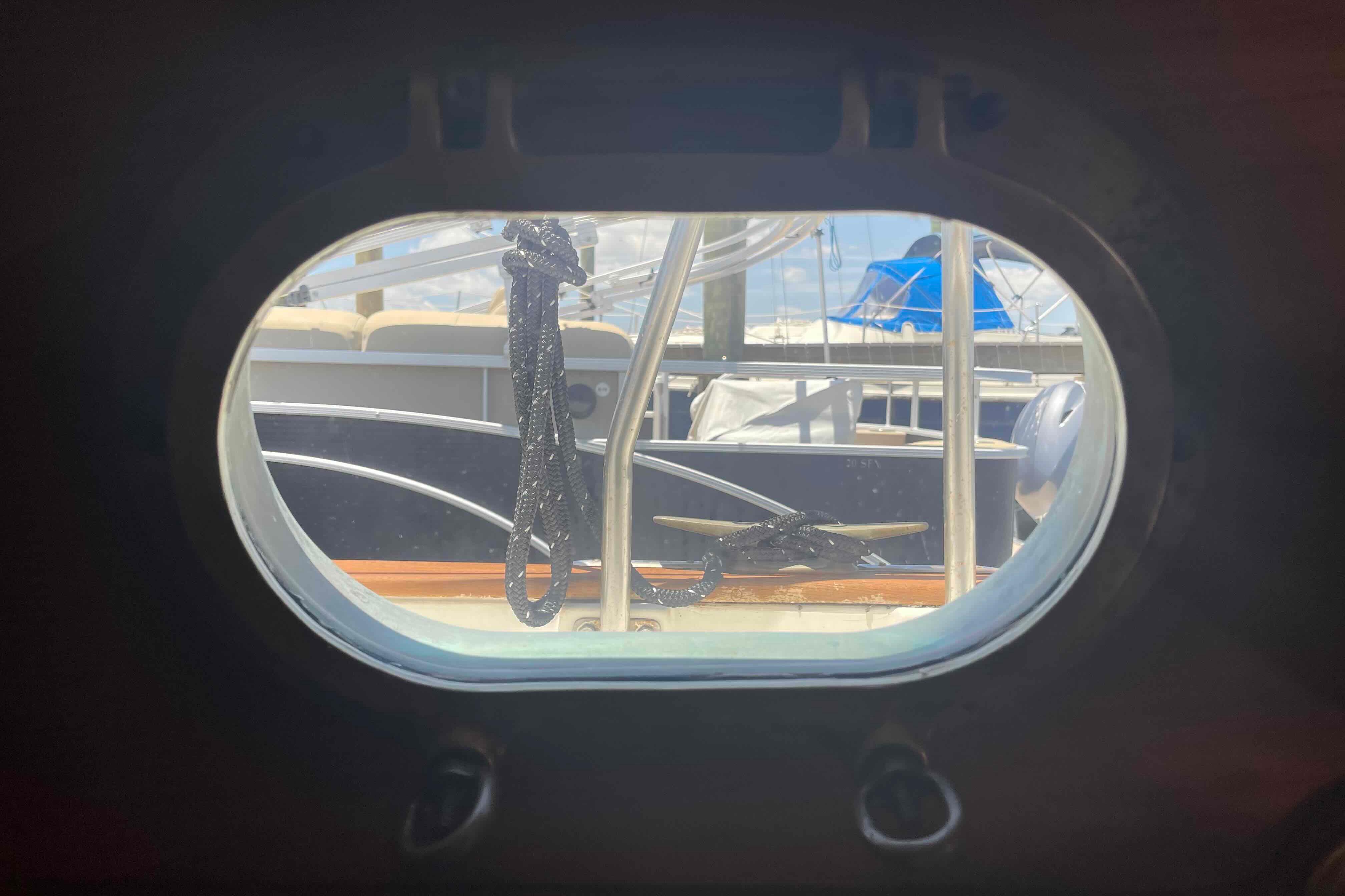 View through a porthole of a 1987 Pacific Seacraft 34 sailboat, showing docked boats.