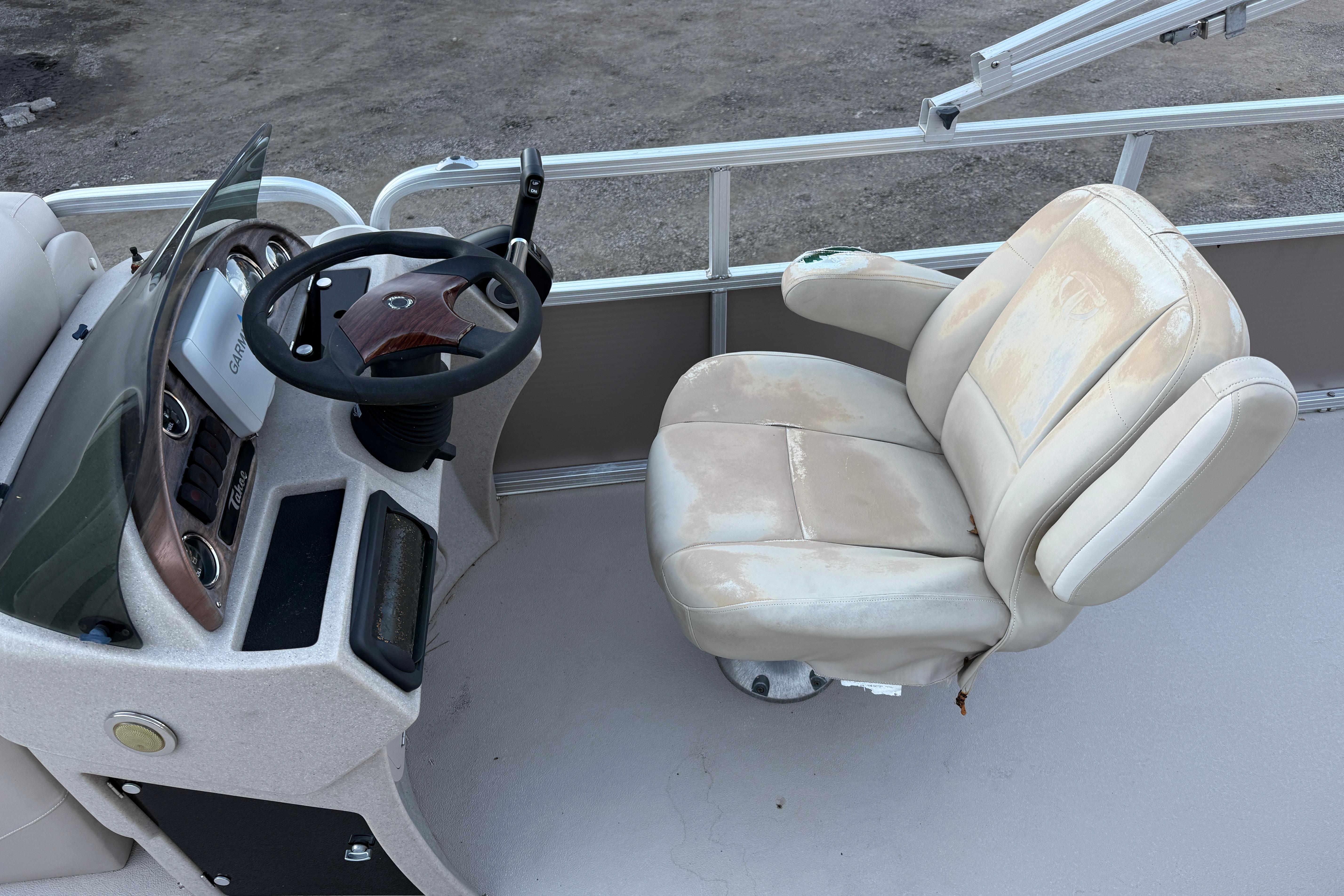 Steering console and seat of 2011 Tahoe Pontoon 2485 DRL boat, showing wear.