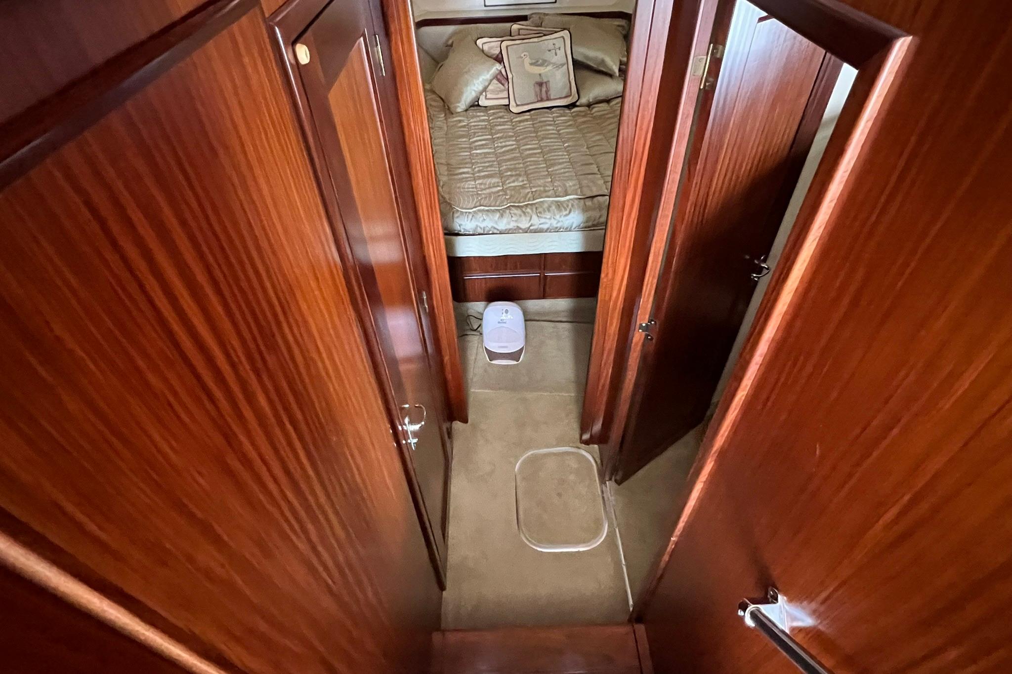 Interior of 1990 Hatteras 41 Convertible yacht with wood paneling and cozy bedroom.