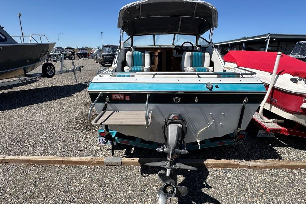 1992 Reinell 192 RM boat with outboard motor, parked in a gravel lot.