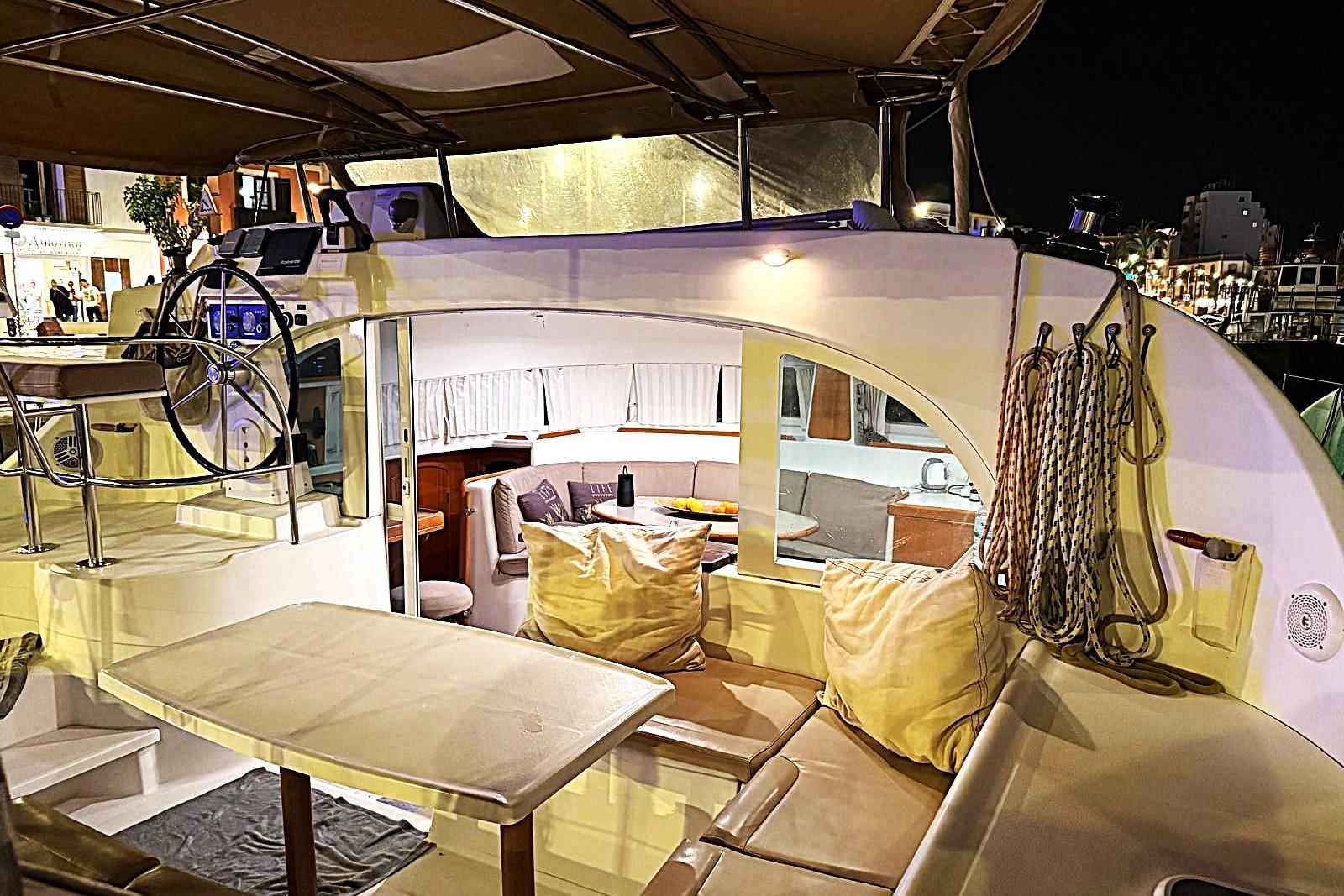 Luxurious 2006 Lagoon 380 S2 catamaran interior at night, featuring cozy seating and navigation area.