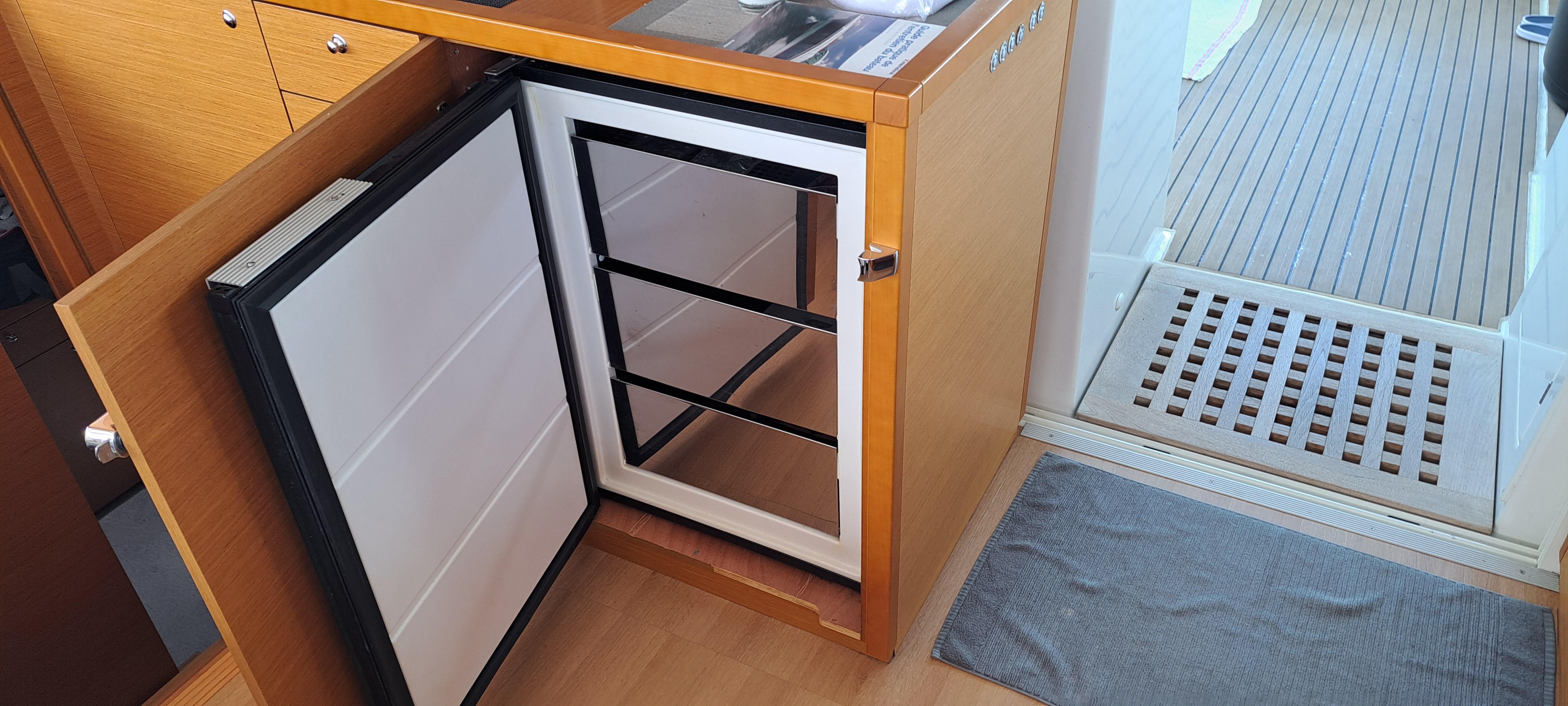 Open fridge in 2017 Lagoon 450 F yacht kitchen, wooden cabinetry, and deck view.