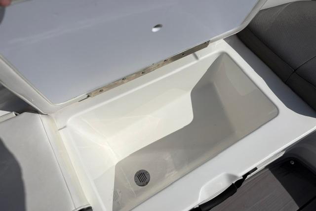 Open storage compartment in 2024 Tahoe T21 boat, featuring a drain plug.