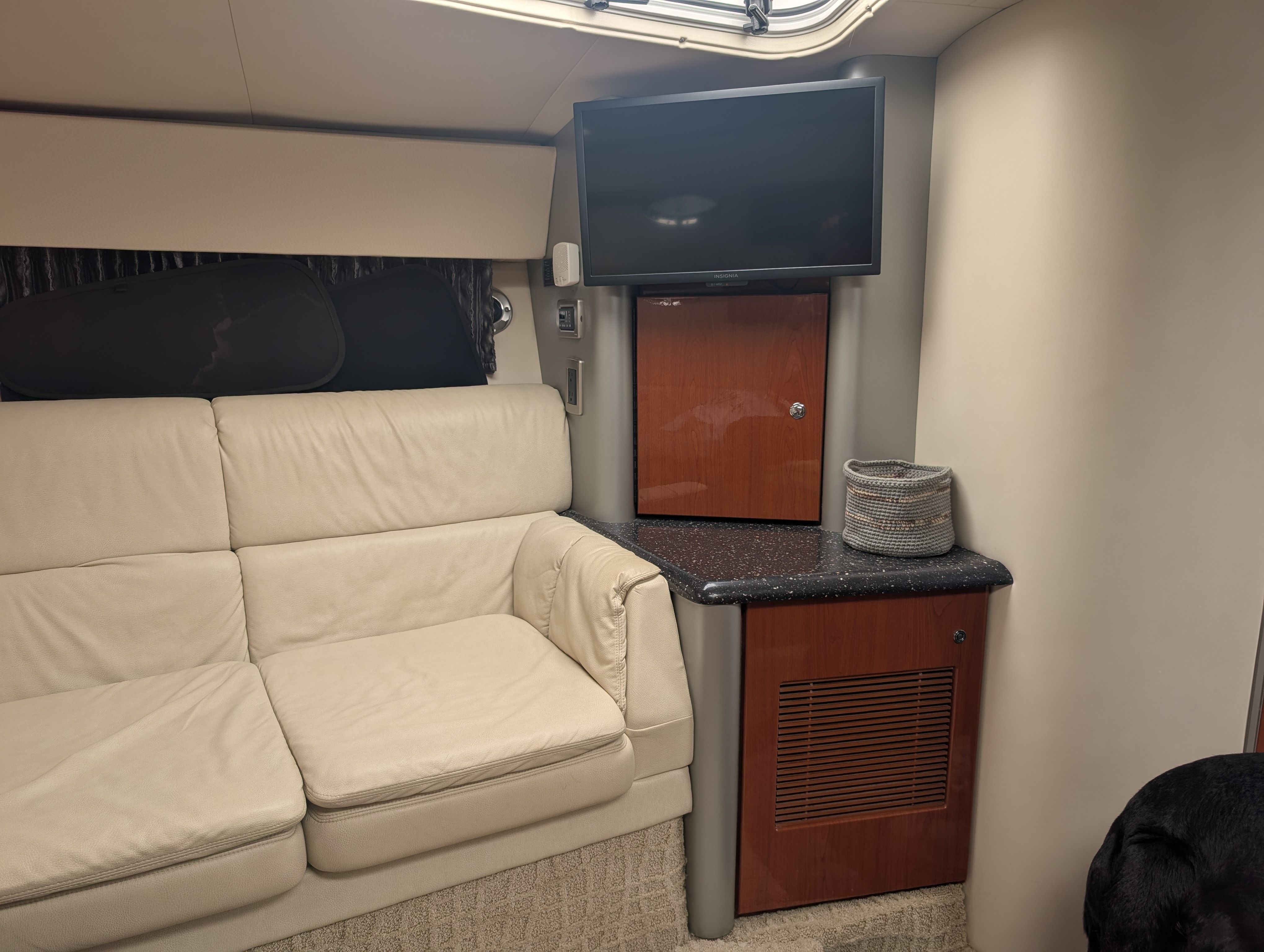 Interior of a yacht with beige sofa, TV, and wooden cabinetry.