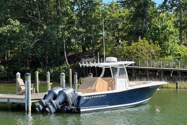 2014 Southport 29 FE boat docked by a wooden pier, surrounded by lush greenery.