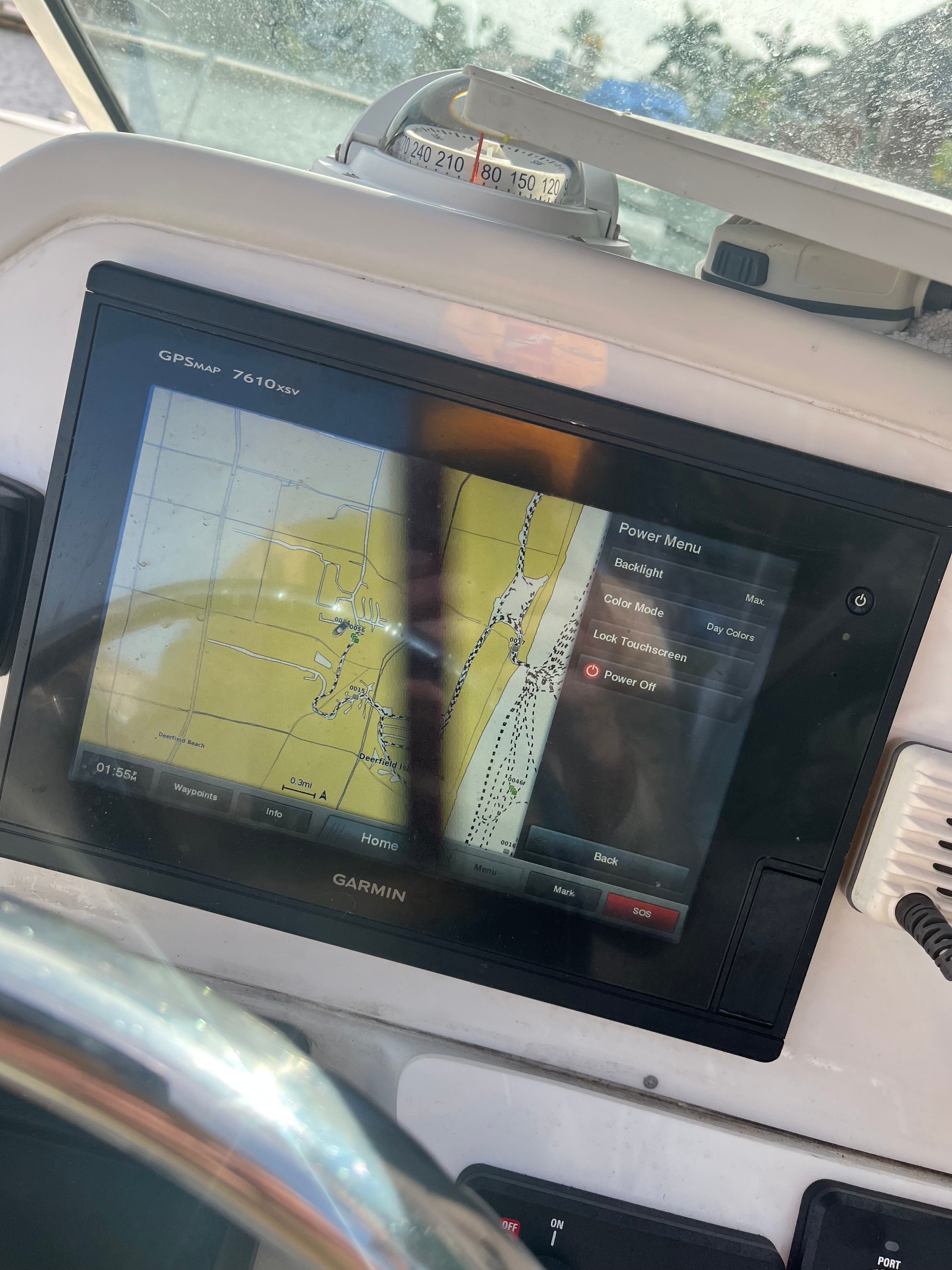 A Garmin GPS chartplotter on a boat displays a navigation map and menu.