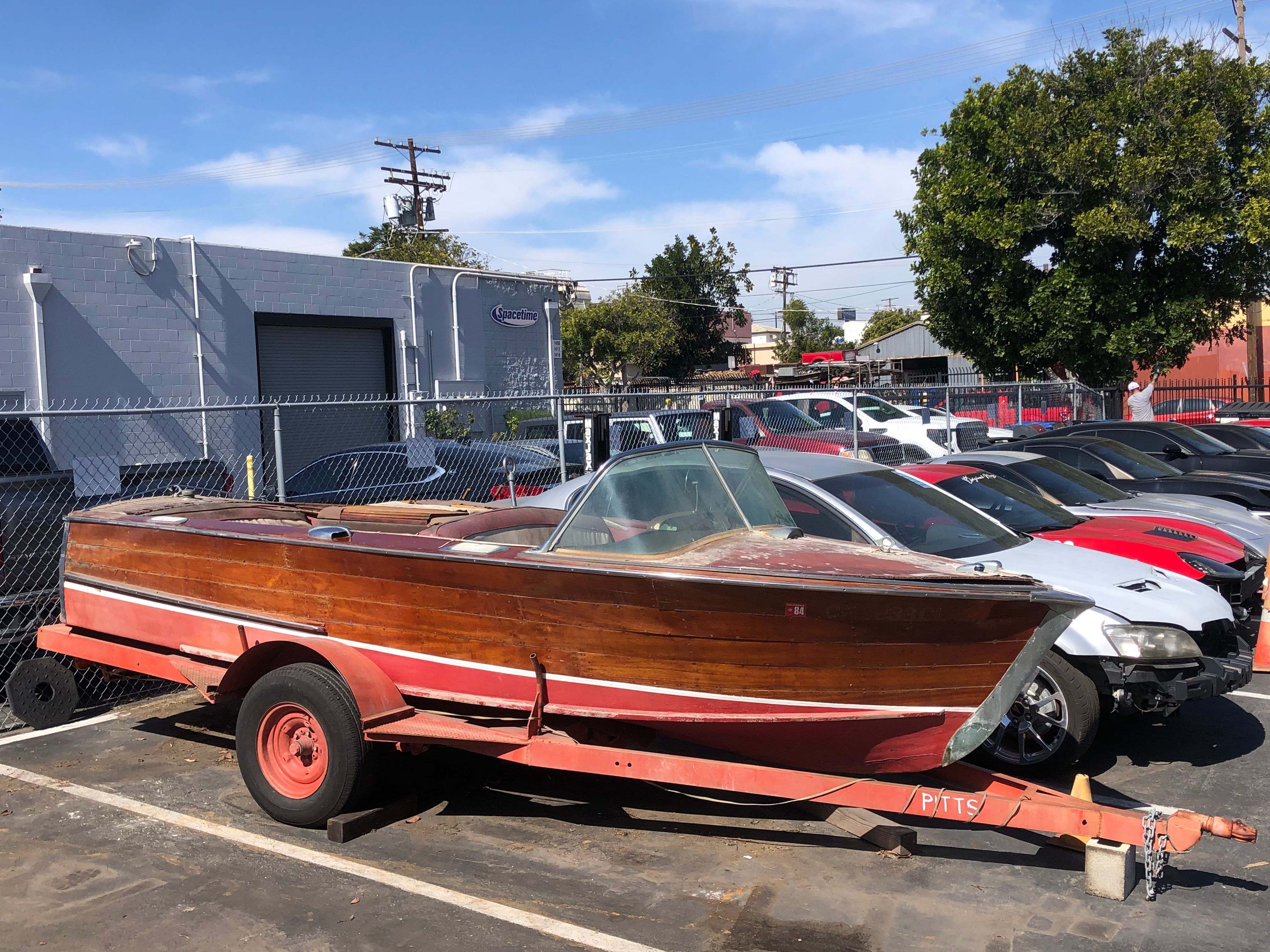 A 1960 Century Resorter on a trailer in a parking lot.