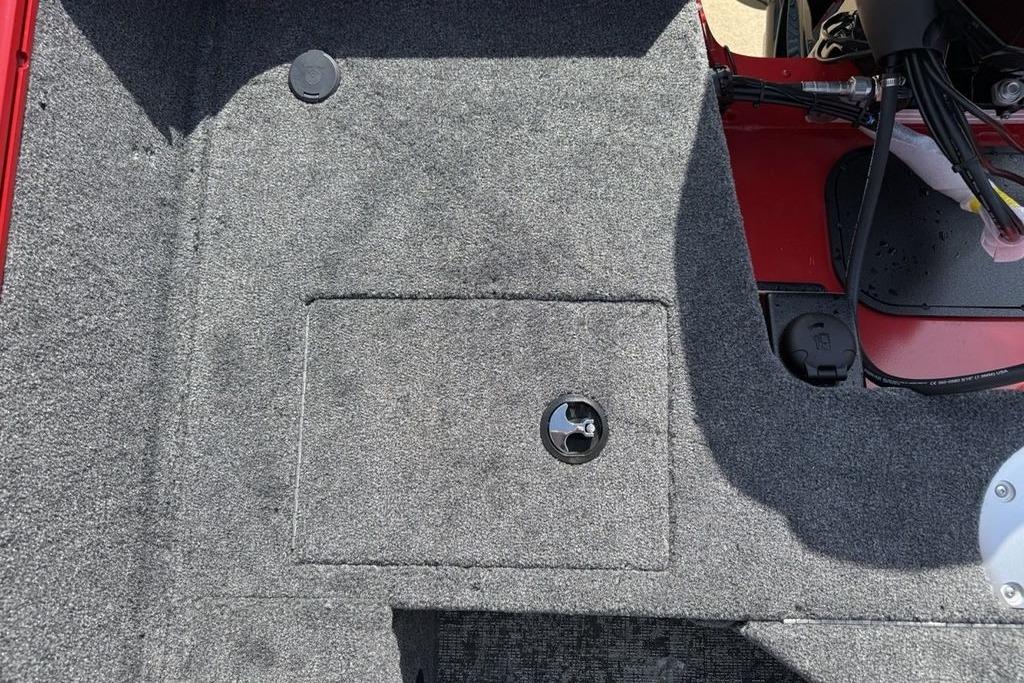 Interior view of 2026 Tracker Pro Guide V-16 SC boat, featuring carpeted flooring and storage compartment.