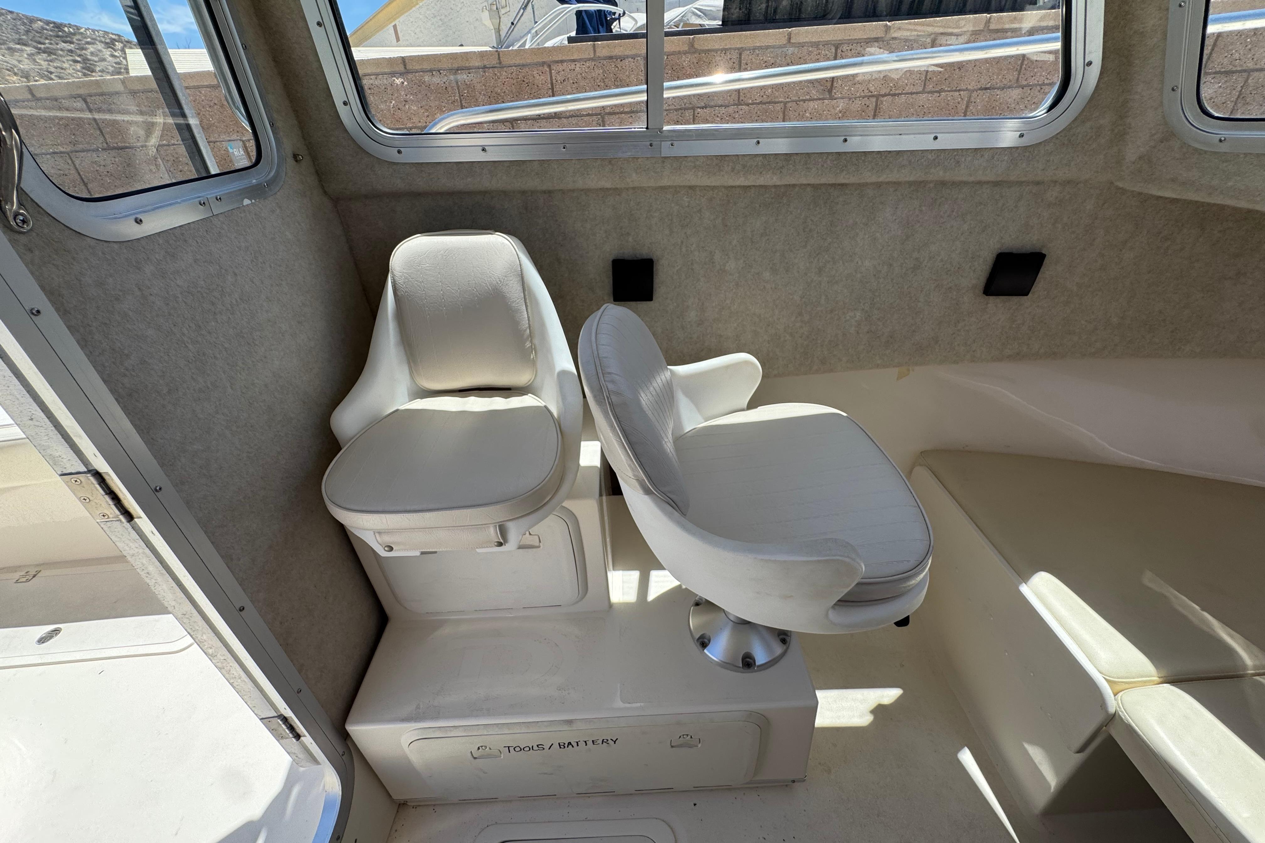 Interior seating of 2017 Defiance Admiral 220 EX boat, featuring two white cushioned chairs.