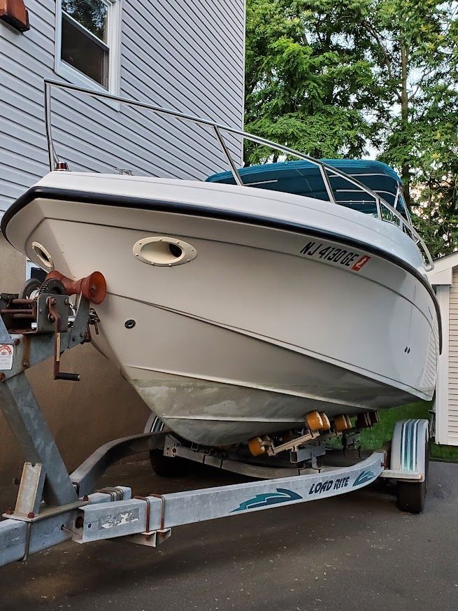 A 1998 Crownline 210 CCR boat on a trailer beside a building.