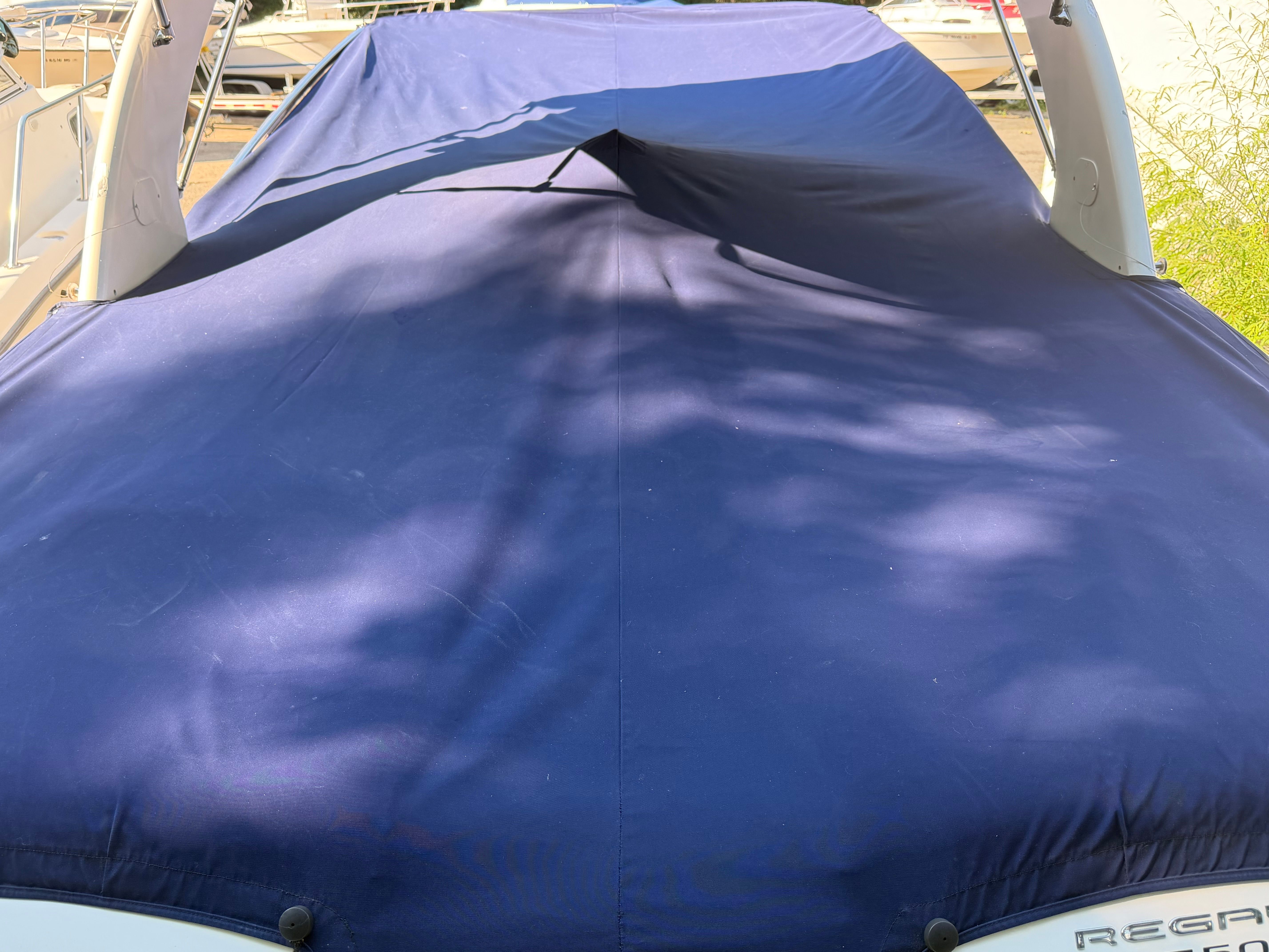 A 2011 Regal 2750 Cuddy boat with a blue cover, docked at a marina.