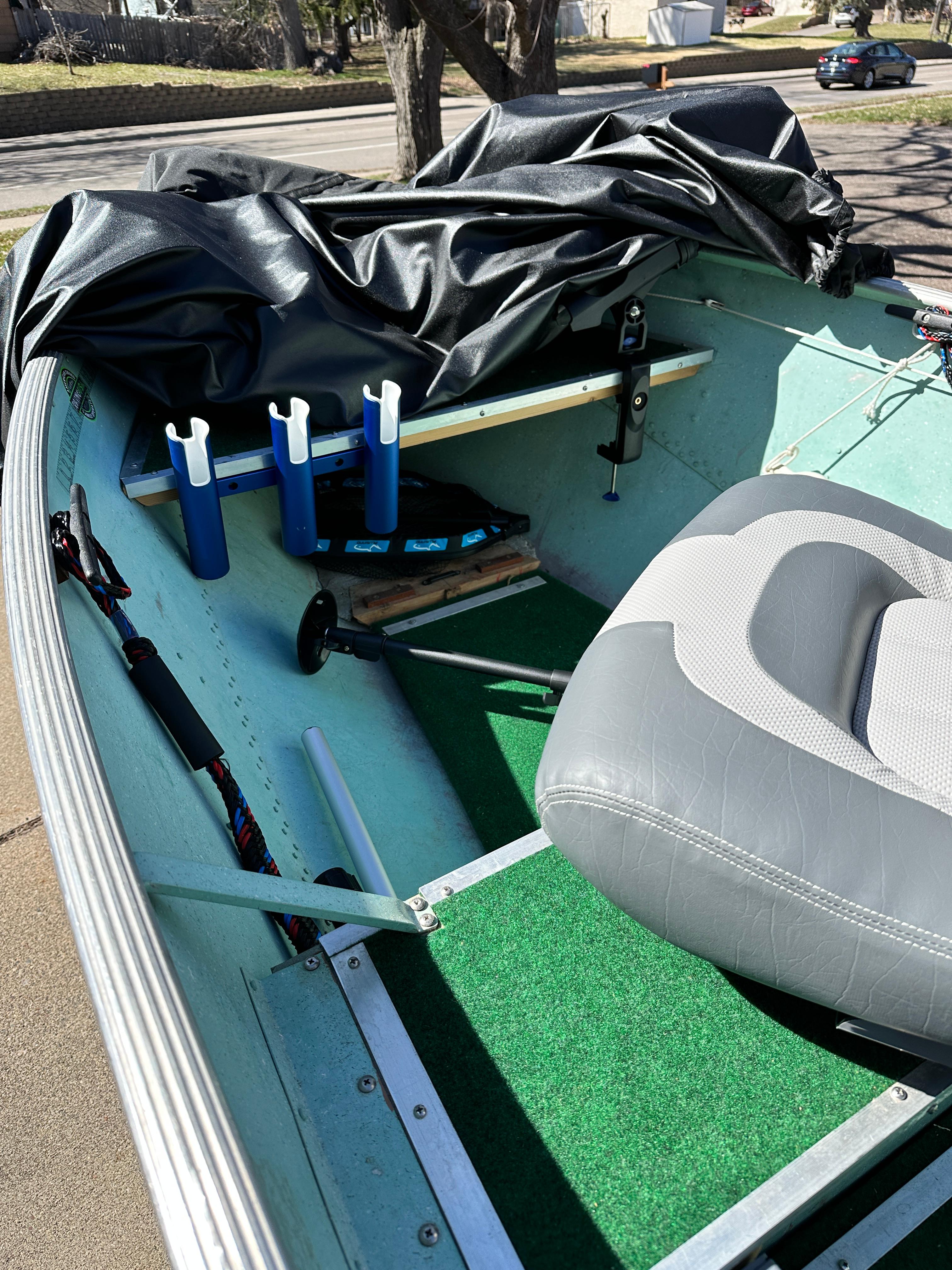 1960 Lund H boat interior with gray seat, rod holders, and green carpet.