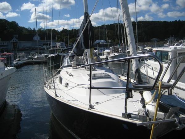 Sailboat docked in a marina with a cloudy sky in the background.