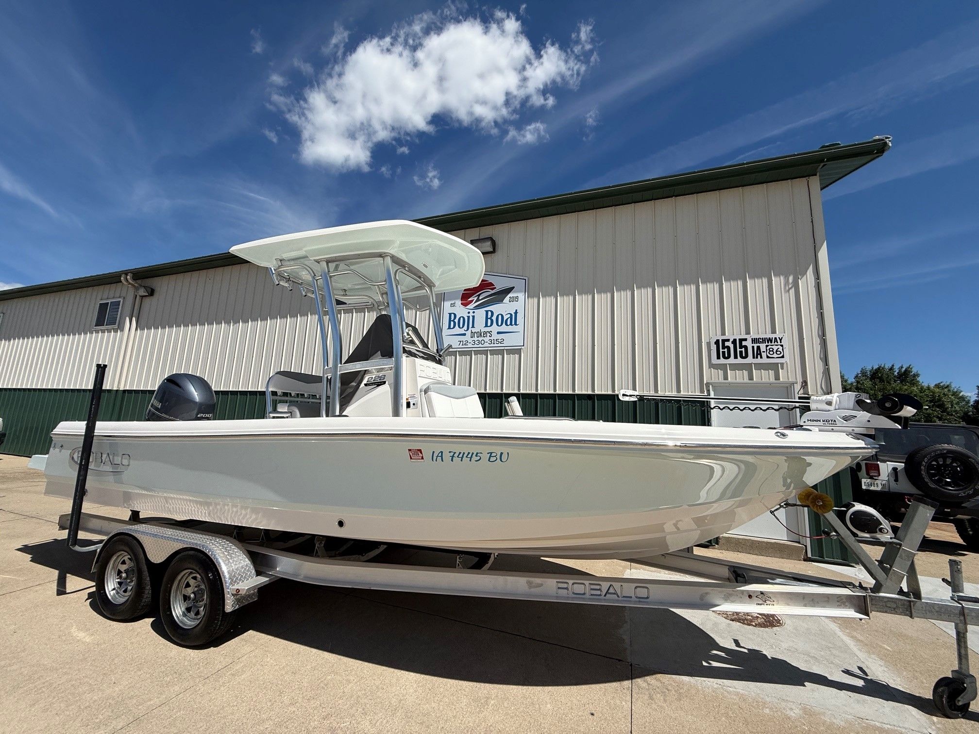 2021 Robalo 226 Cayman boat on trailer in front of building.